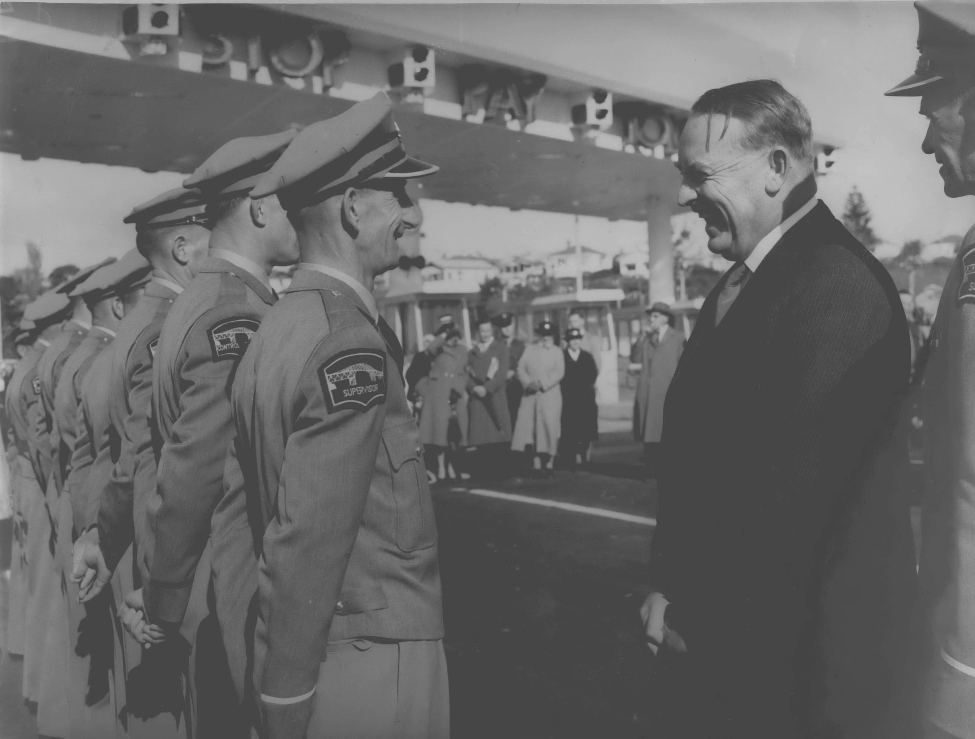 Lord Cobham meeting uniformed members of the Bridge Authority Staff by the Auckland Harbour Bridge.