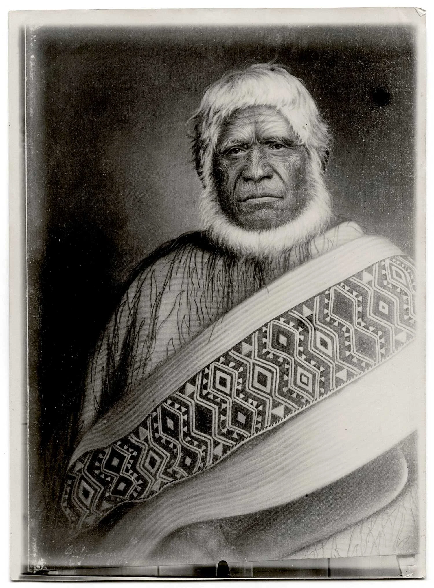 A portrait of a Māori leader with white hair and a beard, wrapped in a cloak, a traditional Māori tattoo on his face.