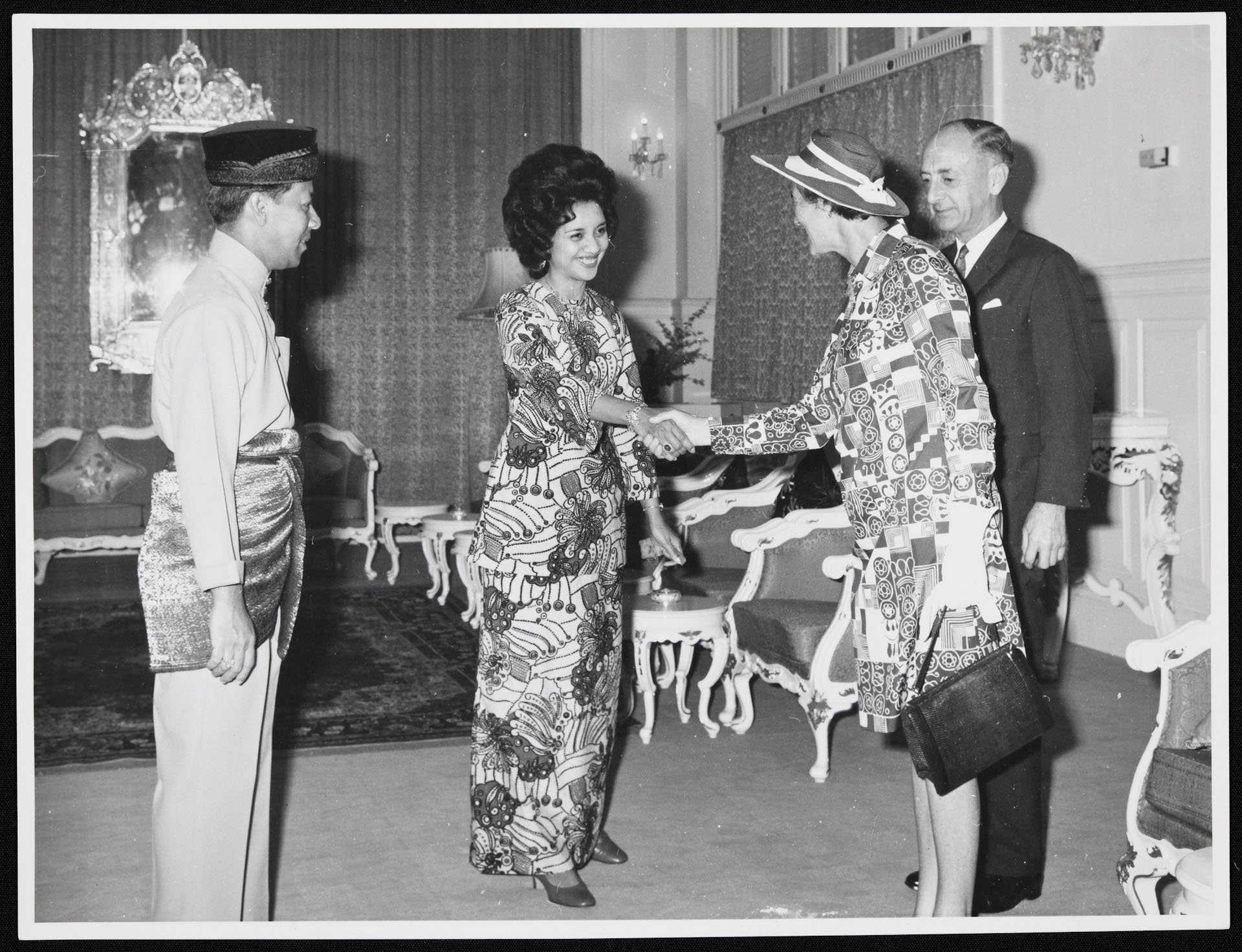2 women shaking hands while 2 men stand next to them.