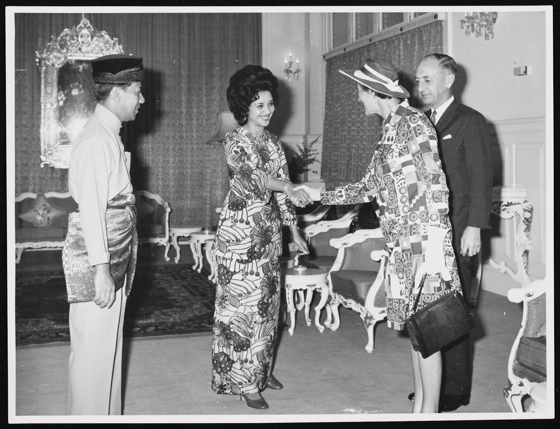 2 women shaking hands while 2 men stand next to them.
