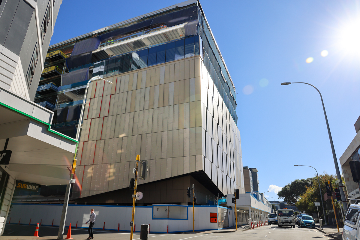 A modern building facade under construction with blue sky behind.