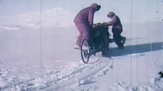 A still from 'One Hundred and Forty Days Under the World'. 2 people push a sled through snow.