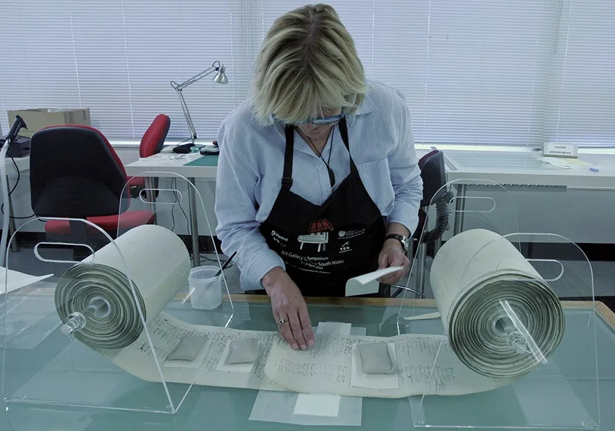 A woman working in a lab on a rolled up scroll