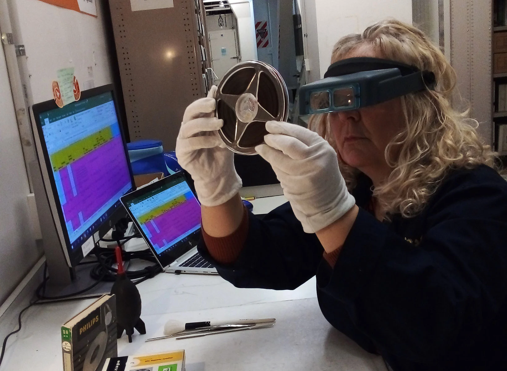 A woman sitting in front of a monitor assessing an open reel
