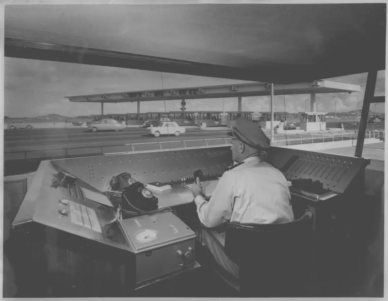 Black and white photo of a man from behind in a toll booth