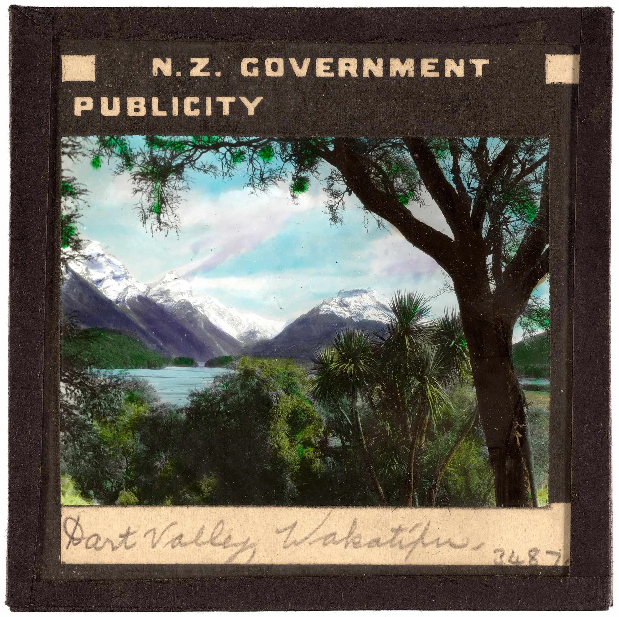 Snow-capped mountain peaks and lush green trees surround a blue lake.