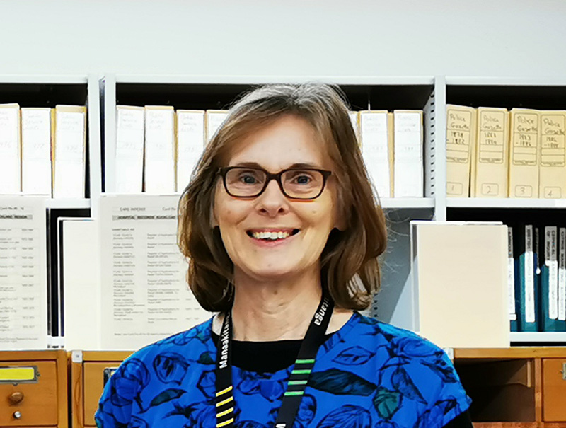 Sarah Mathieson standing in front of archival boxes.