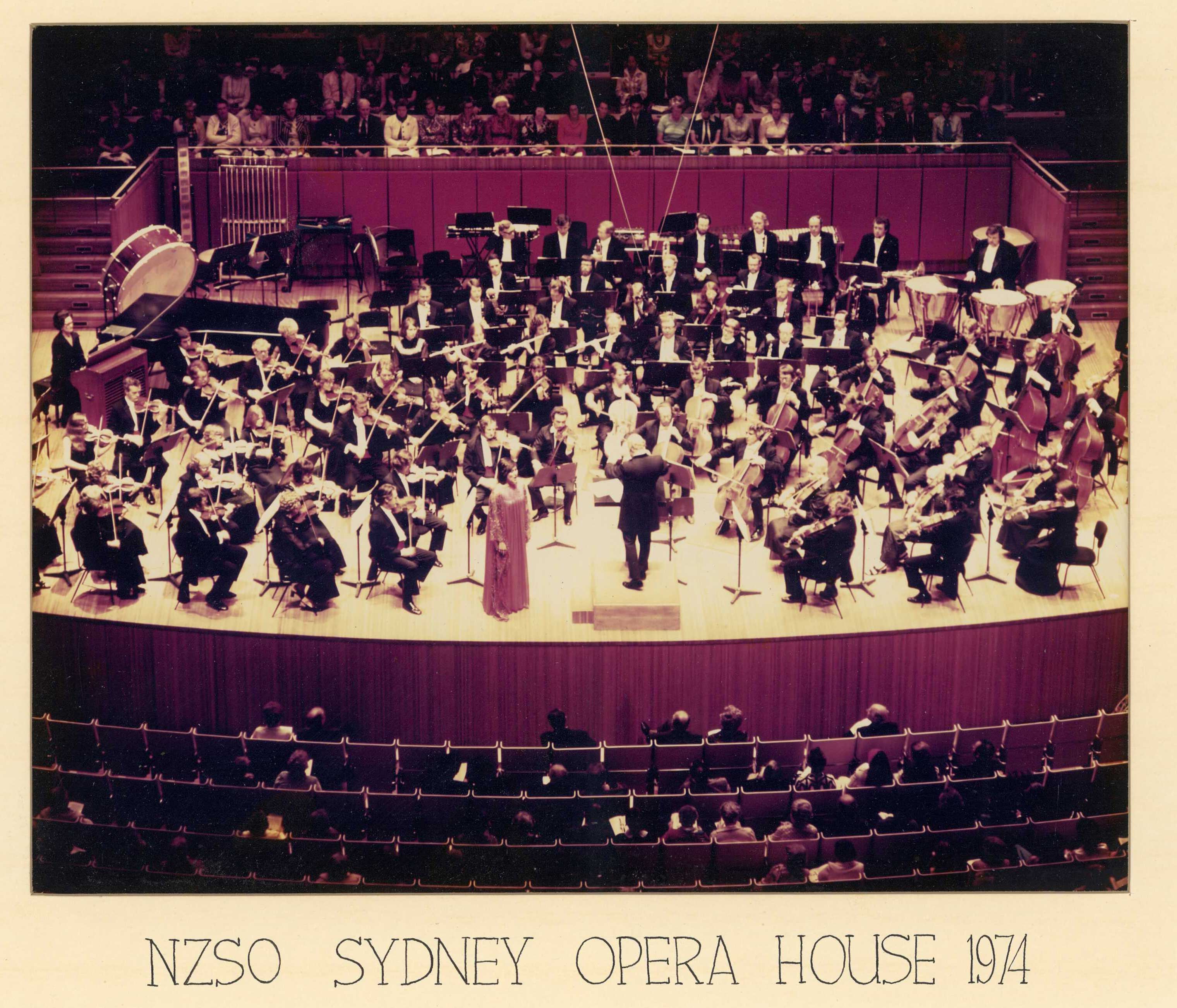 Old coloured photo of an orchestra performing on a stage