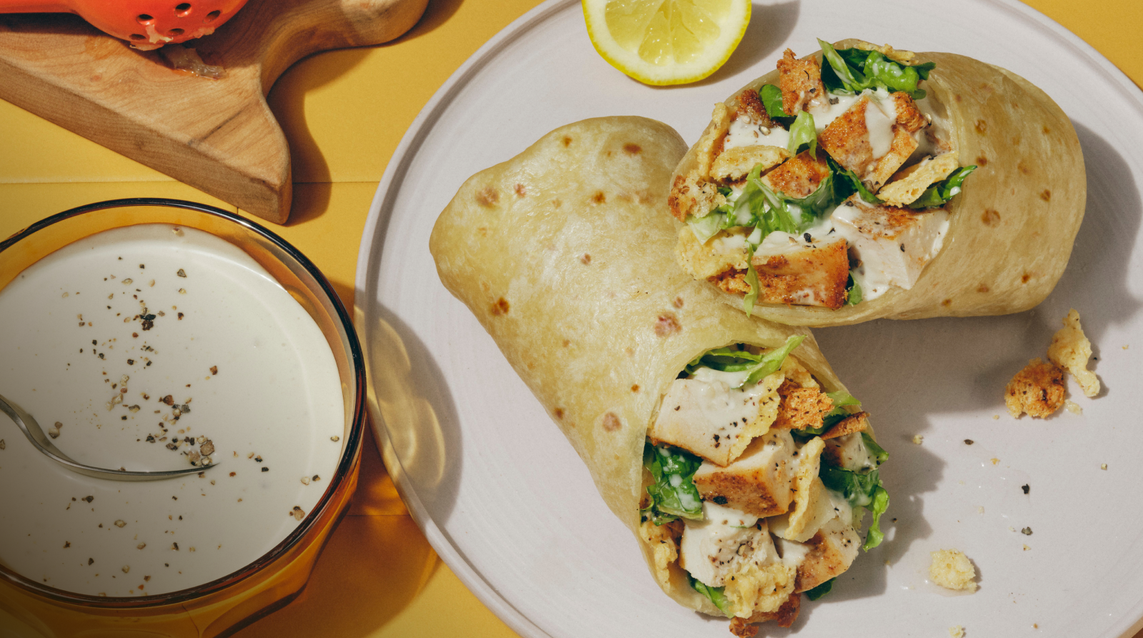 Classic Chicken Caesar wrap on a plate with a yellow tile background