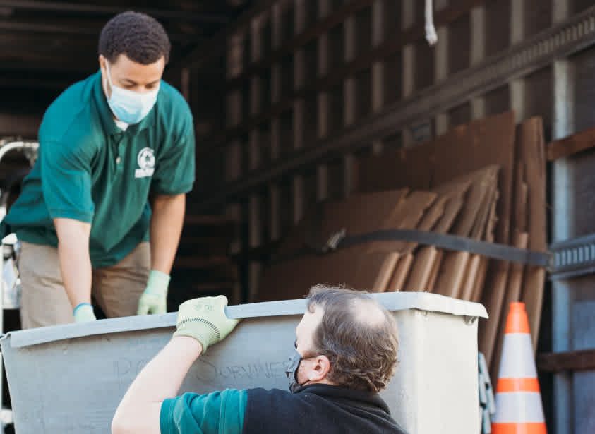 two men lifting a container into a truck