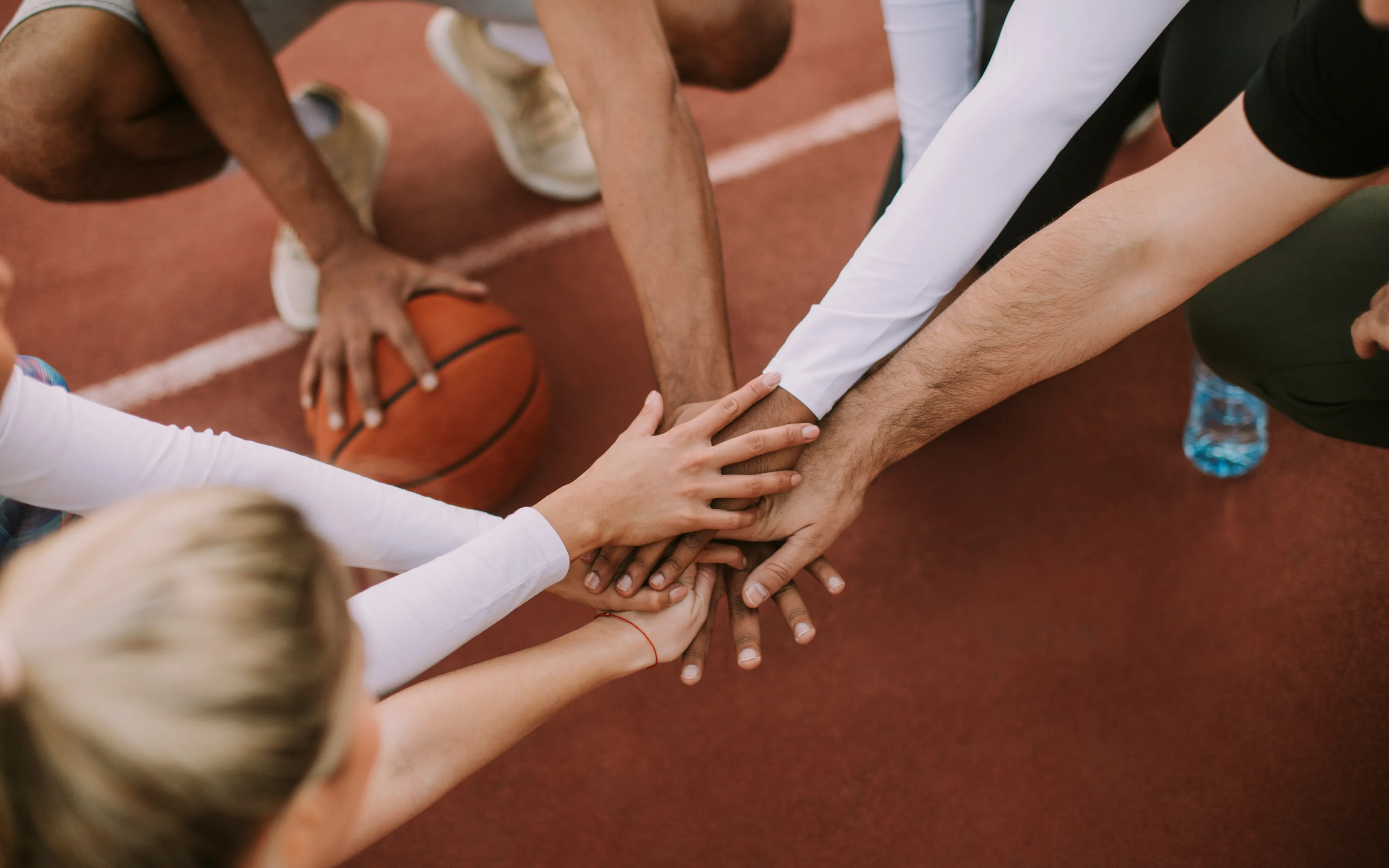 basketball team putting their hands in middle