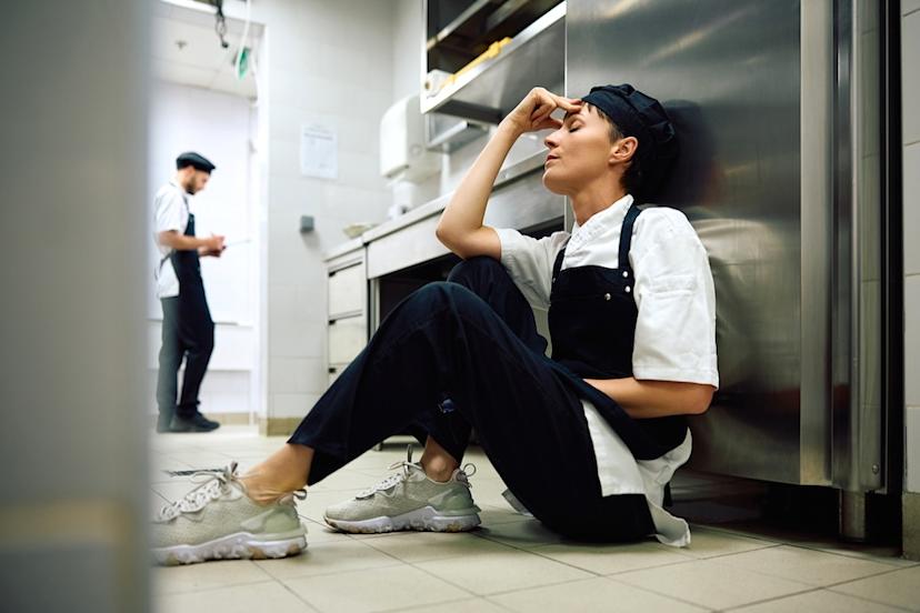 Worn-out employee sits on kitchen floor