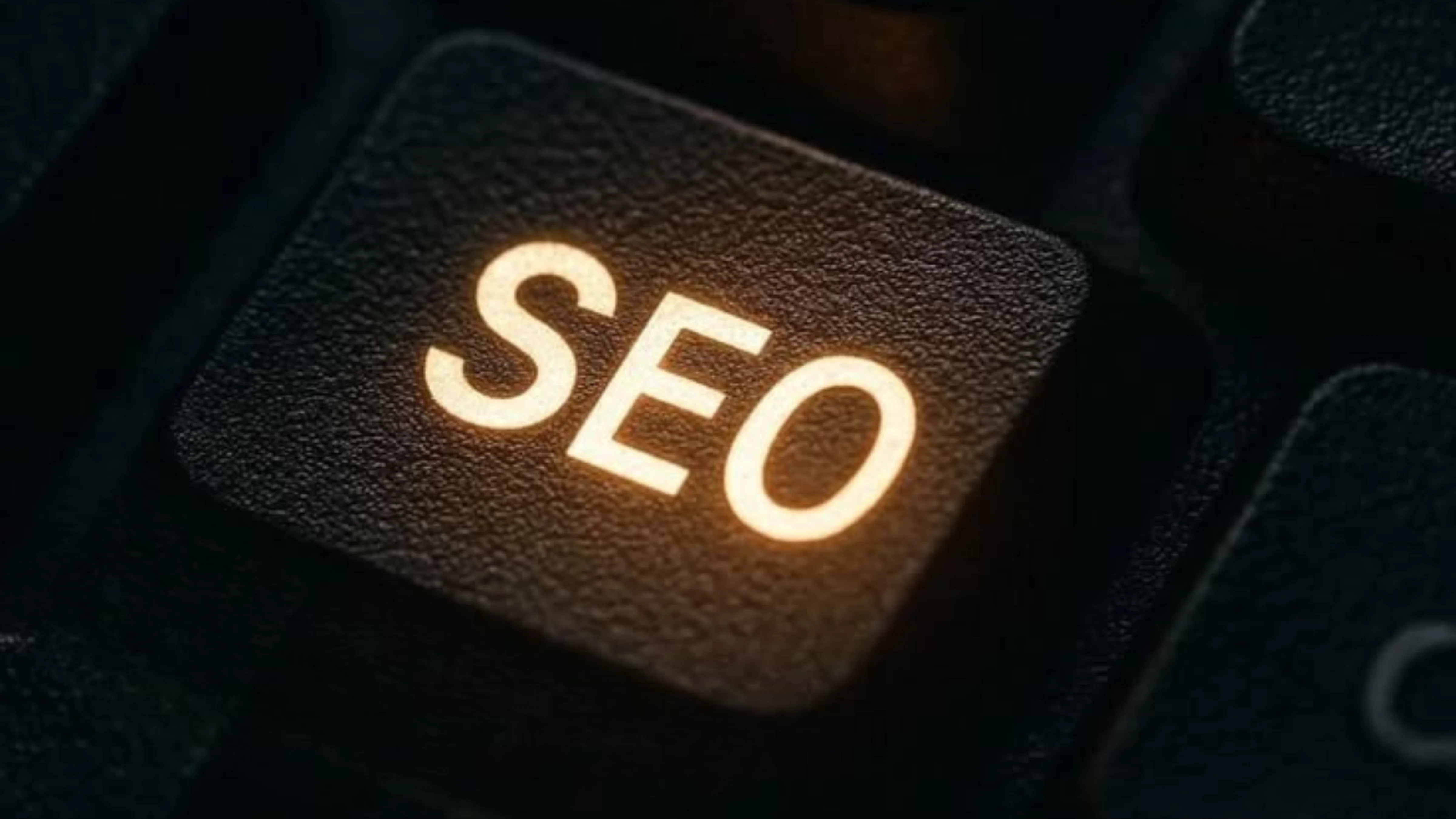 Close-up of a black, backlit keyboard key with the word "SEO" illuminated in yellow/orange.