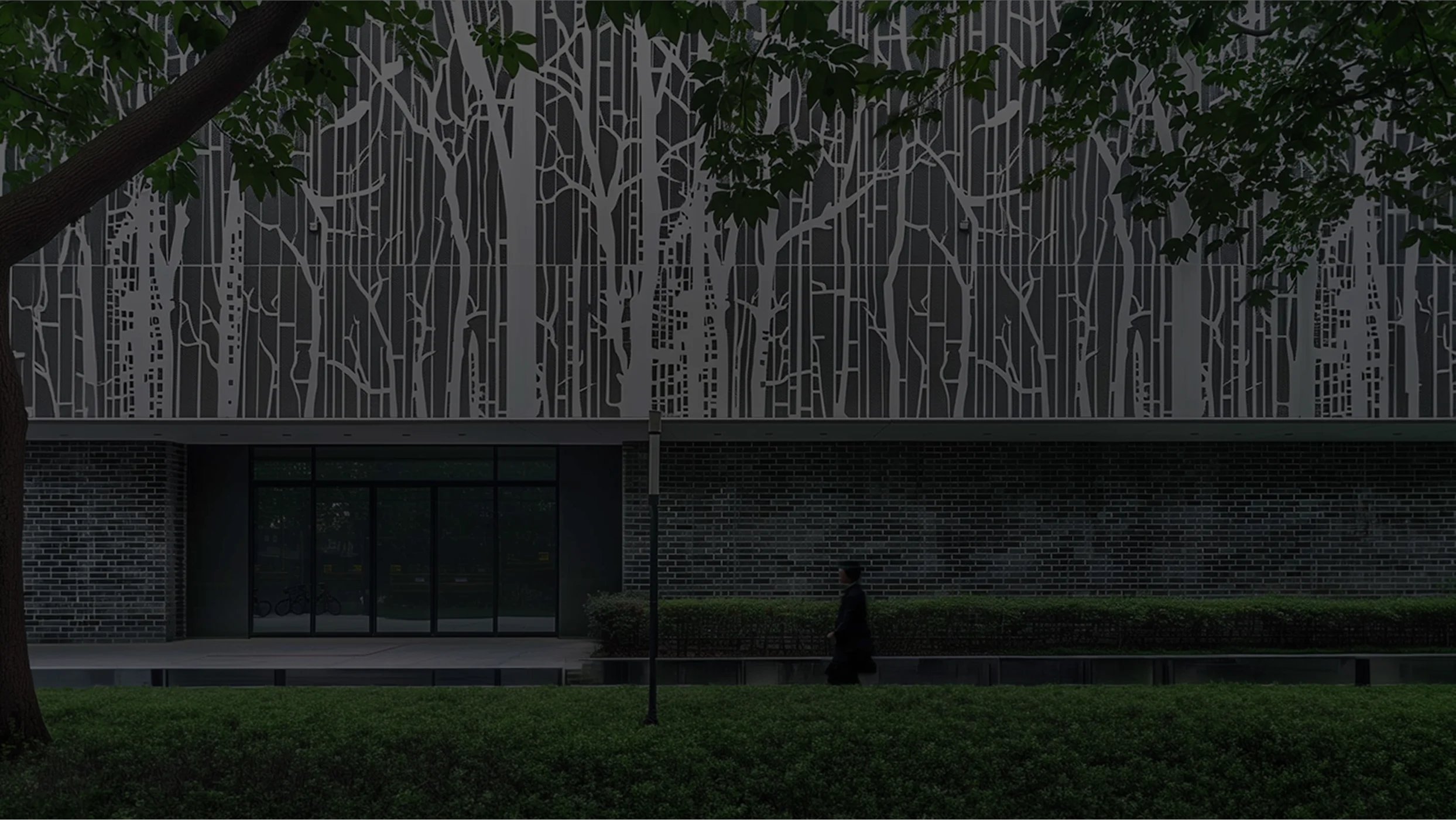 Modern architectural facade with geometric decorations in the shape of trees and surrounding urban green areas.