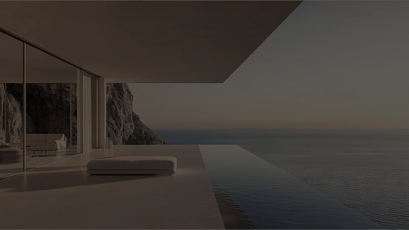 Terrace of a modern luxury architecture with sun loungers, overlooking the ocean during a golden sunset.