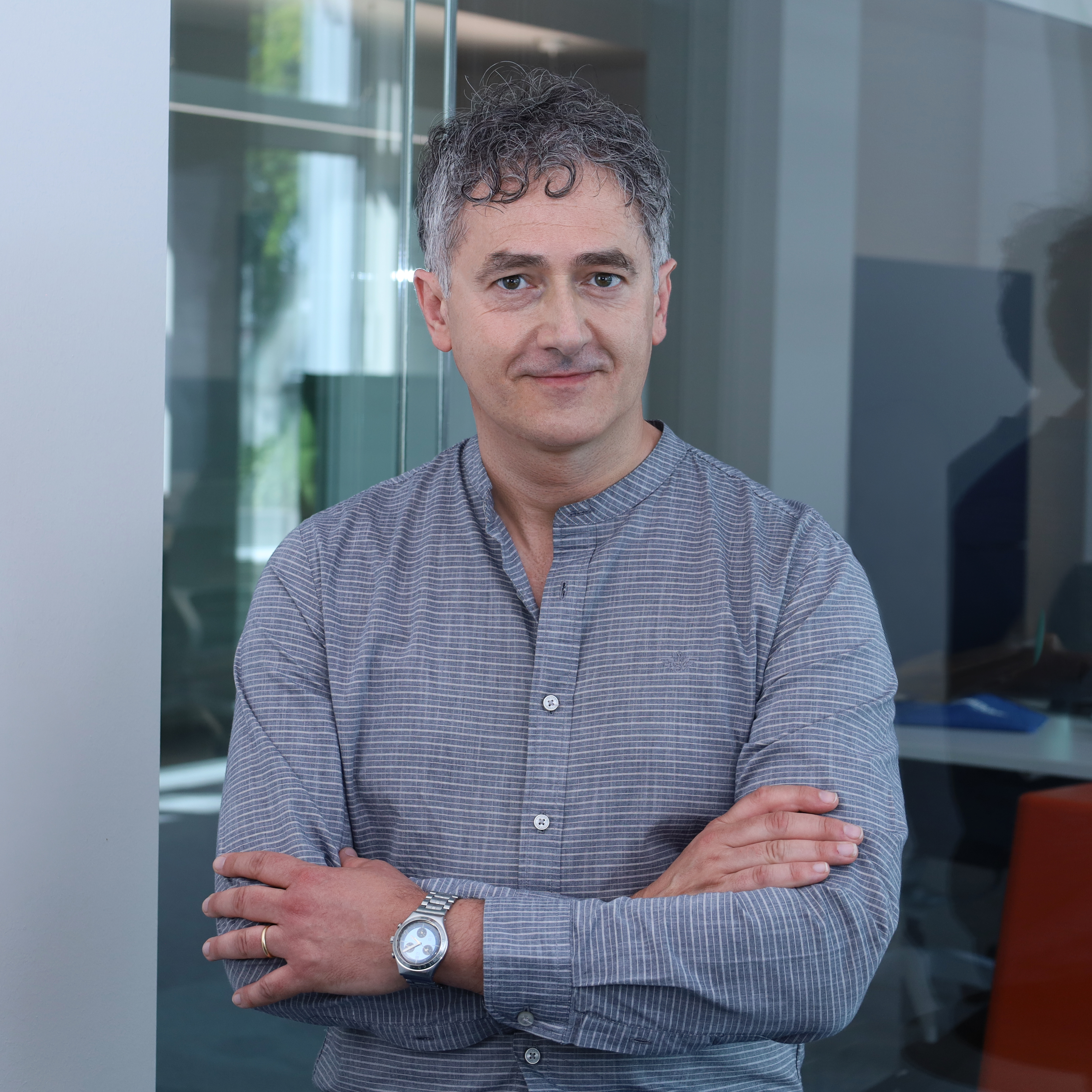 Portrait of Marco Zamboni, Chief AI Officer at Redify, standing with his arms crossed in a modern office.
