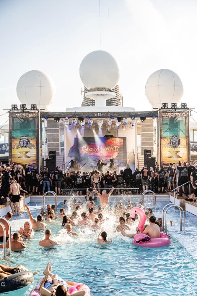 Poolparty mit Live-Band, Menschen planschen, pinker Flamingo-Schwimmring, Bühne mit Lichtshow