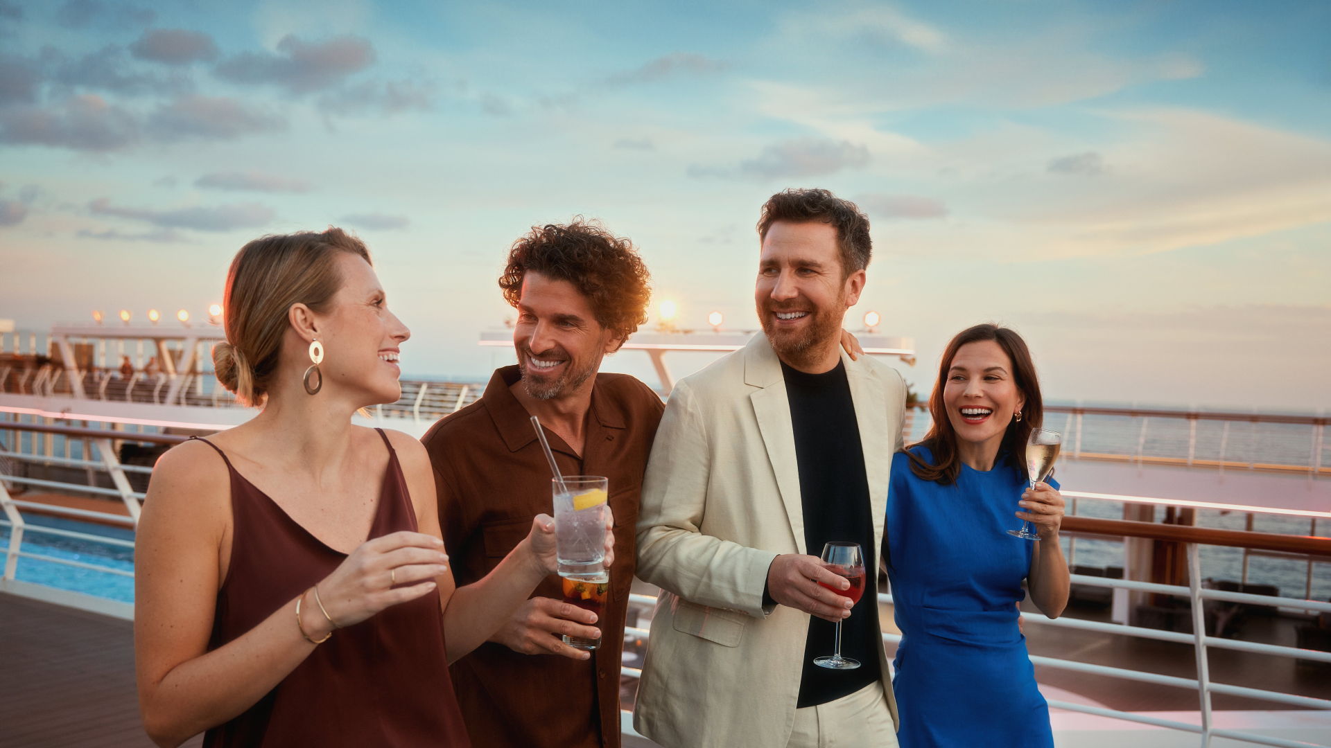 Vier Personen spazieren am frühen Abend auf einem Kreuzfahrtschiff der Mein Schiff® Flotte.