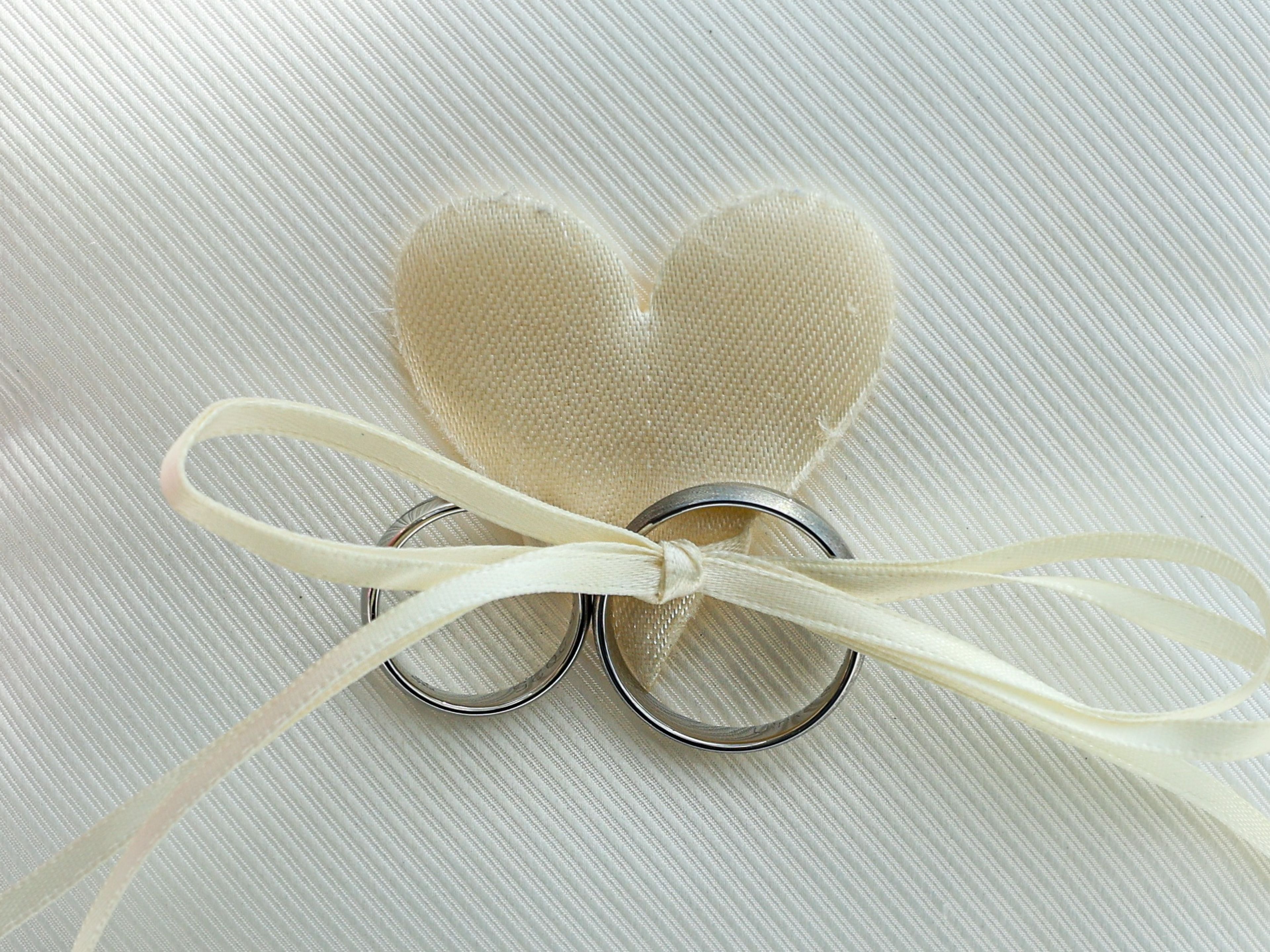 Verlobung an Board Weiße Kissen mit Ringen und Herz, rosa Hintergrund.