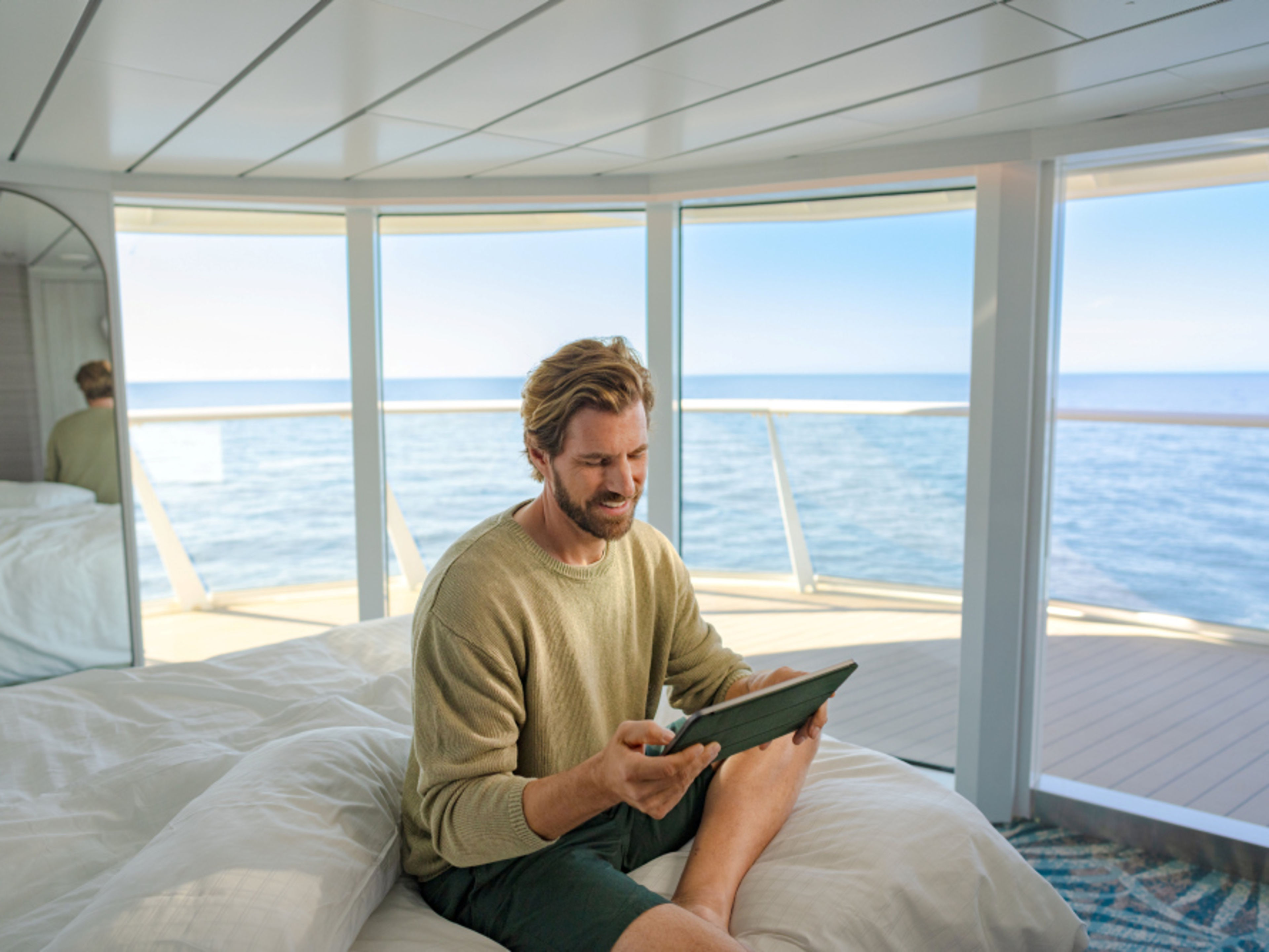 Extra Leistungen buchen Mann sitzt mit Tablet auf Bett