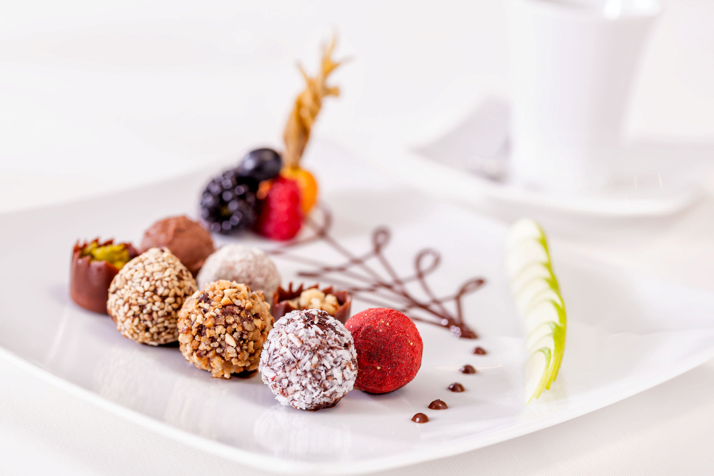 Pralinen auf weißem Teller mit Beeren und Schokoladendekor.