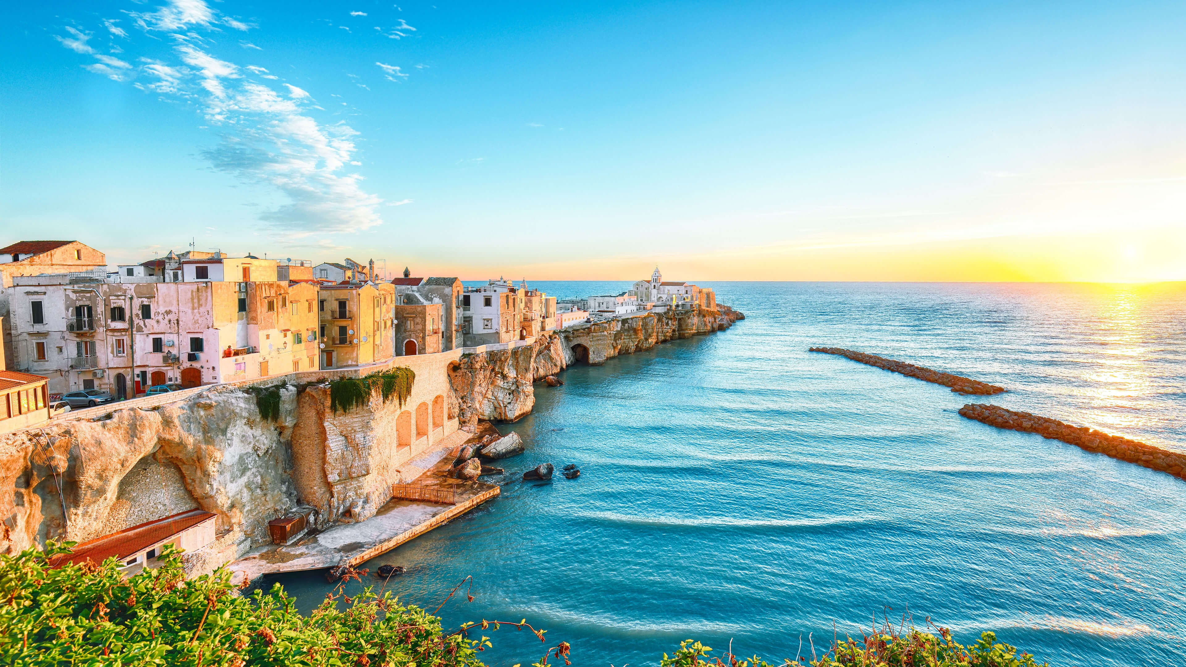Küstenstadt Vieste bei Sonnenuntergang, bunte Häuser, blaues Meer.