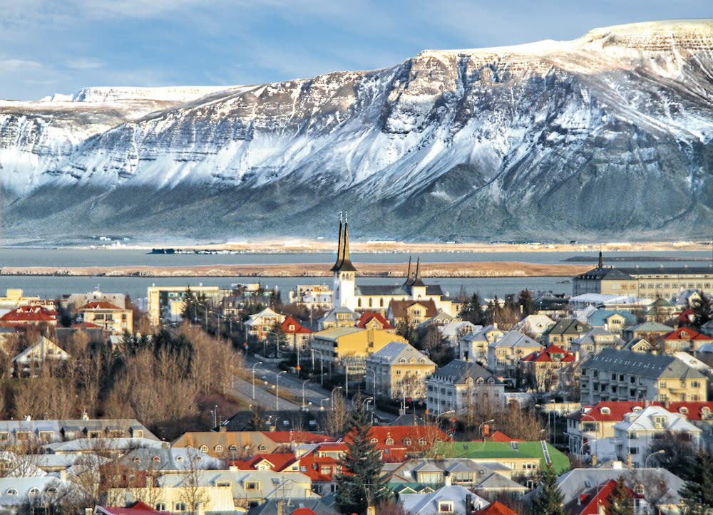 Reykjavik mit schneebedeckten Bergen im Hintergrund, bunte Häuser.