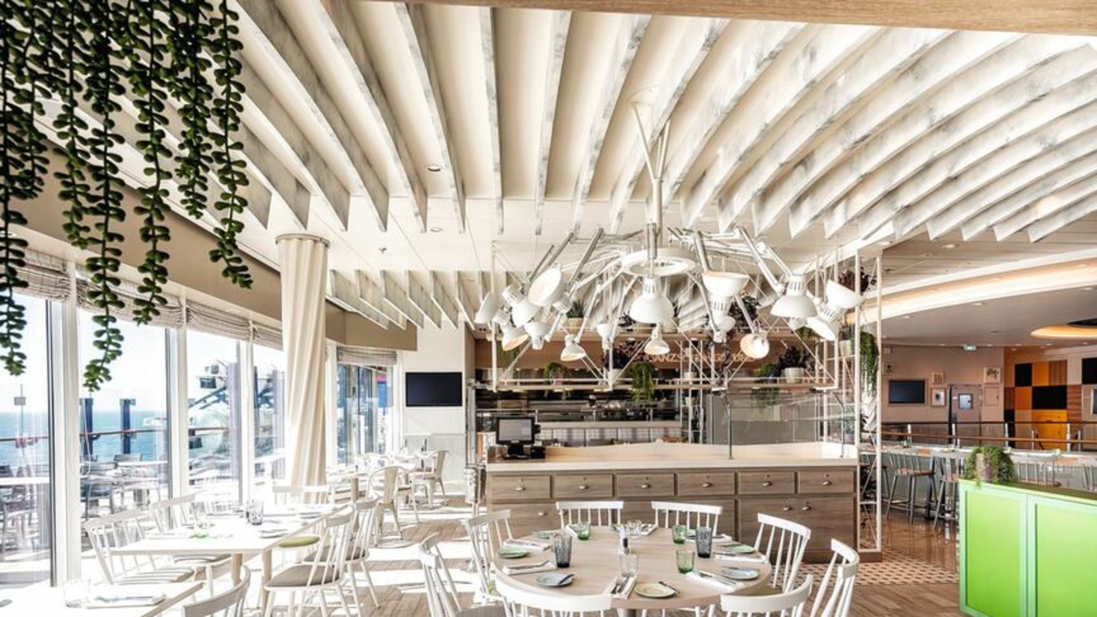 Ganz schön gesund Bistro Mein Schiff 1, Mein Schiff 2 und Mein Schiff 7 Helles Restaurant mit weißen Stühlen, Holzboden, grünen Akzenten.