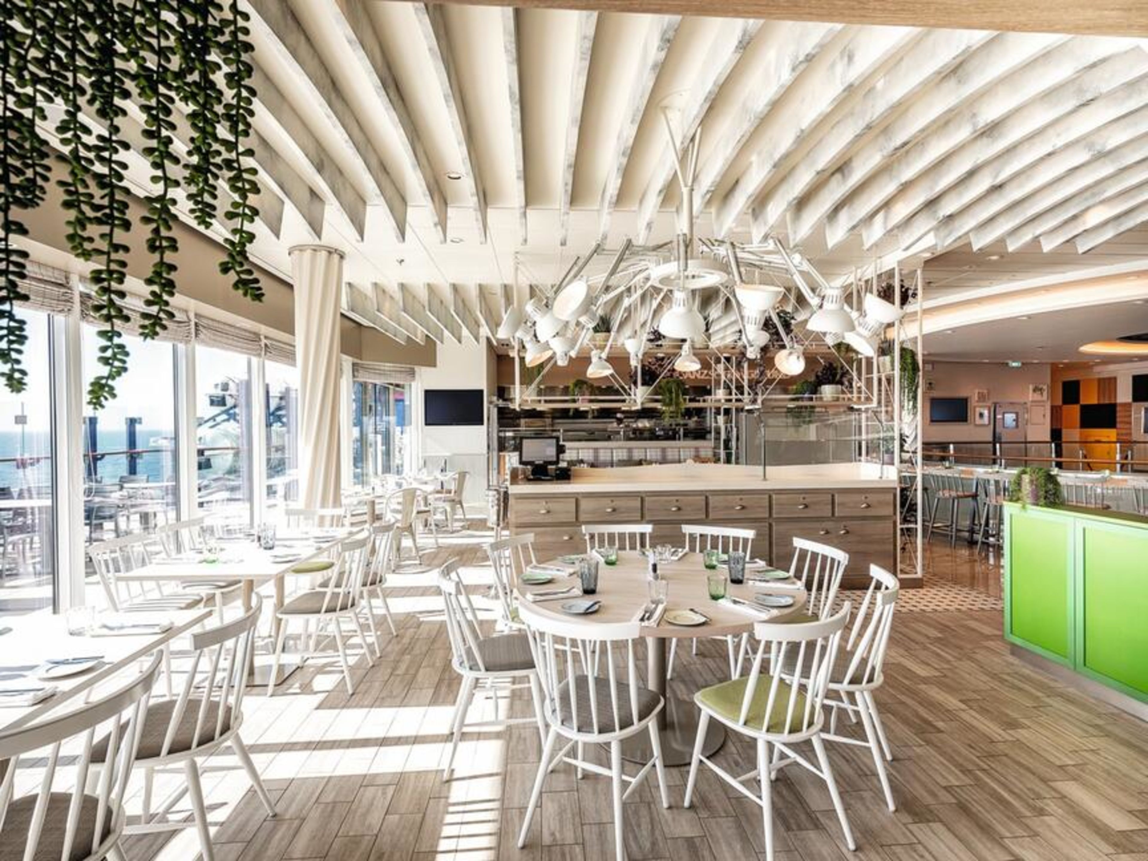 Ganz schön gesund Bistro Mein Schiff 1, Mein Schiff 2 und Mein Schiff 7 Helles Restaurant mit weißen Stühlen, Holzboden, grünen Akzenten.