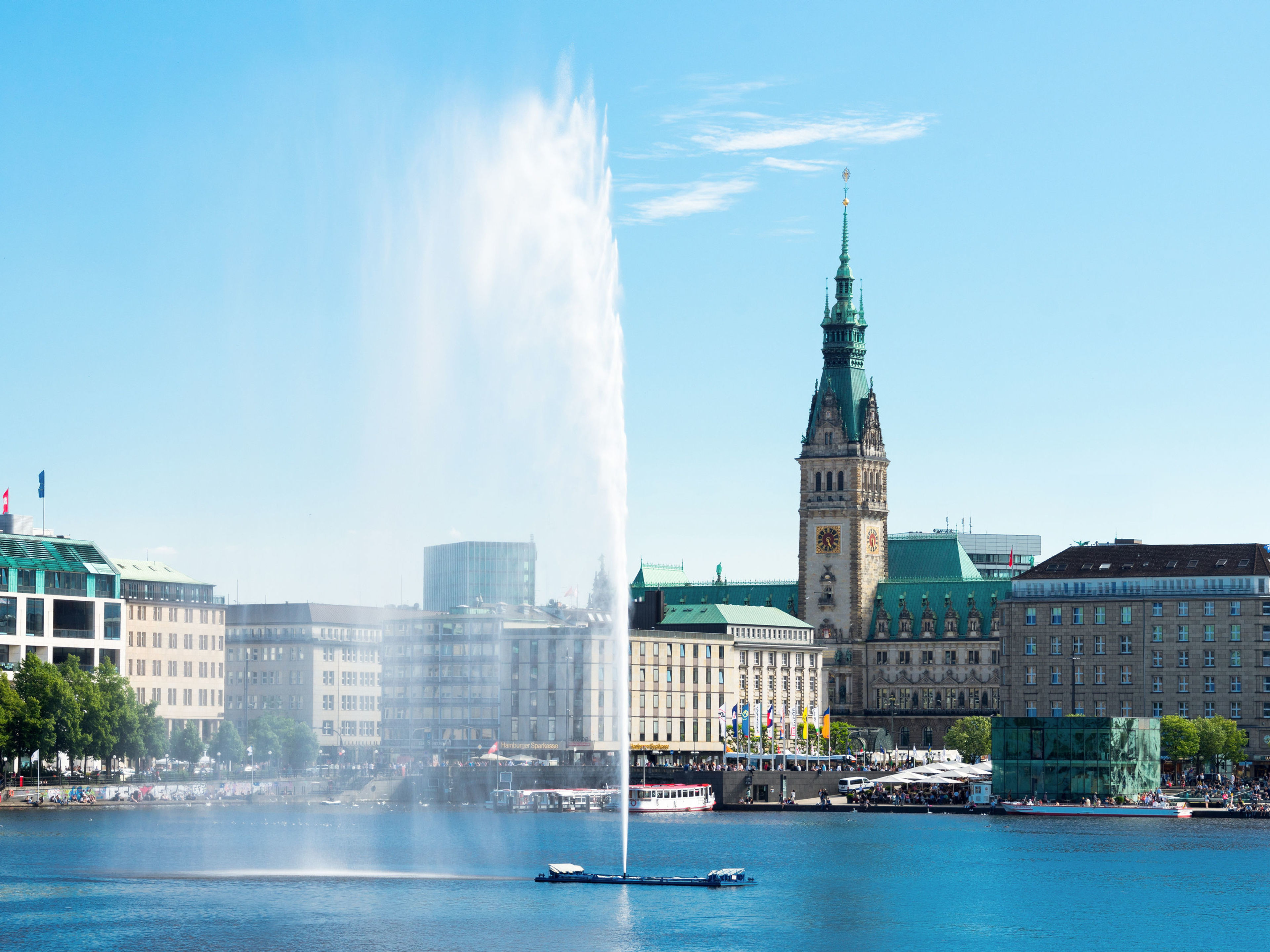 Hamburg Hamburger Rathaus und Alsterfontäne bei klarem Himmel.