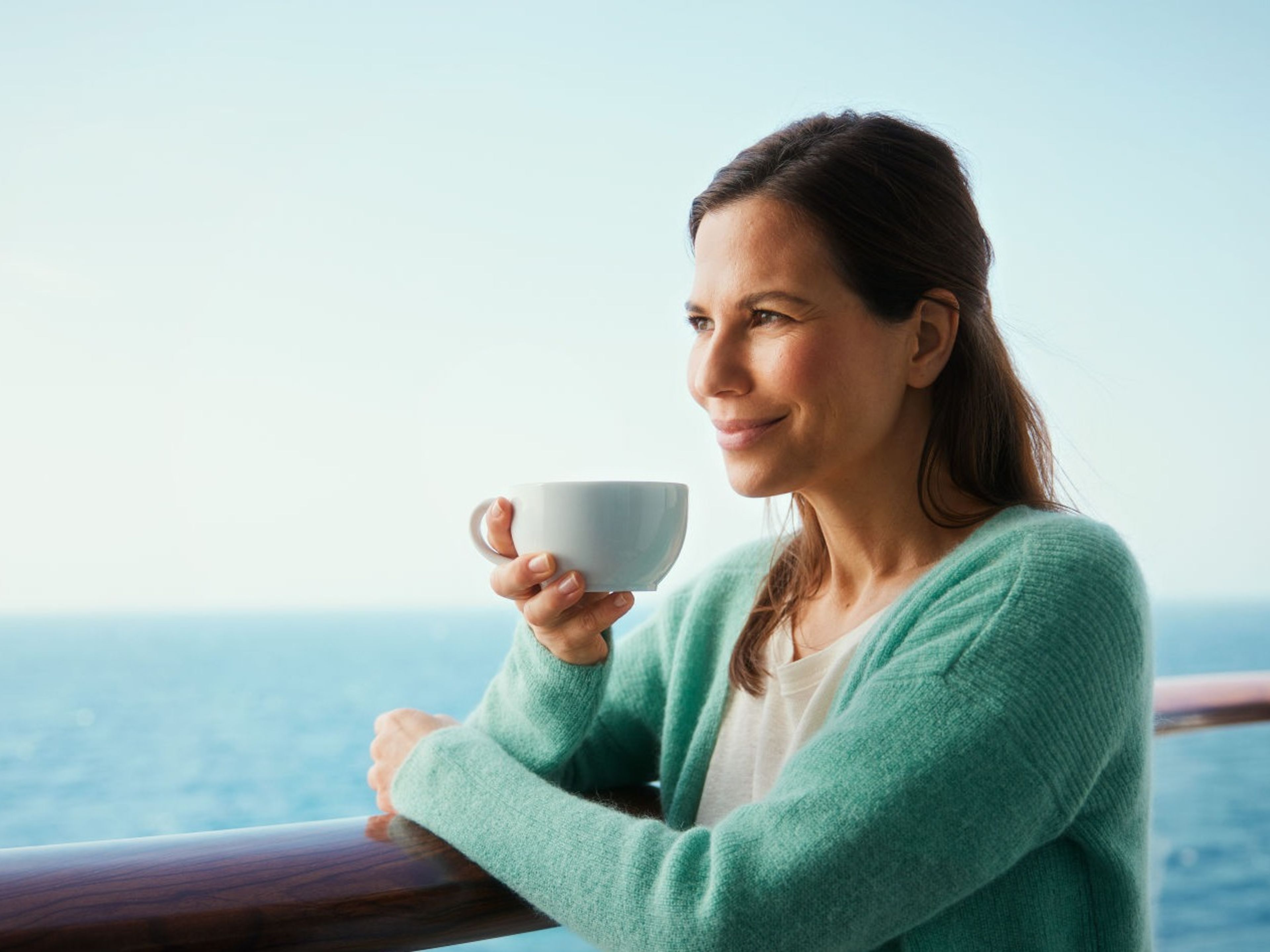 Frau genießt Kaffee auf Kreuzfahrtschiff, Meerblick. Frau genießt Kaffee auf Kreuzfahrtschiff, Meerblick.
