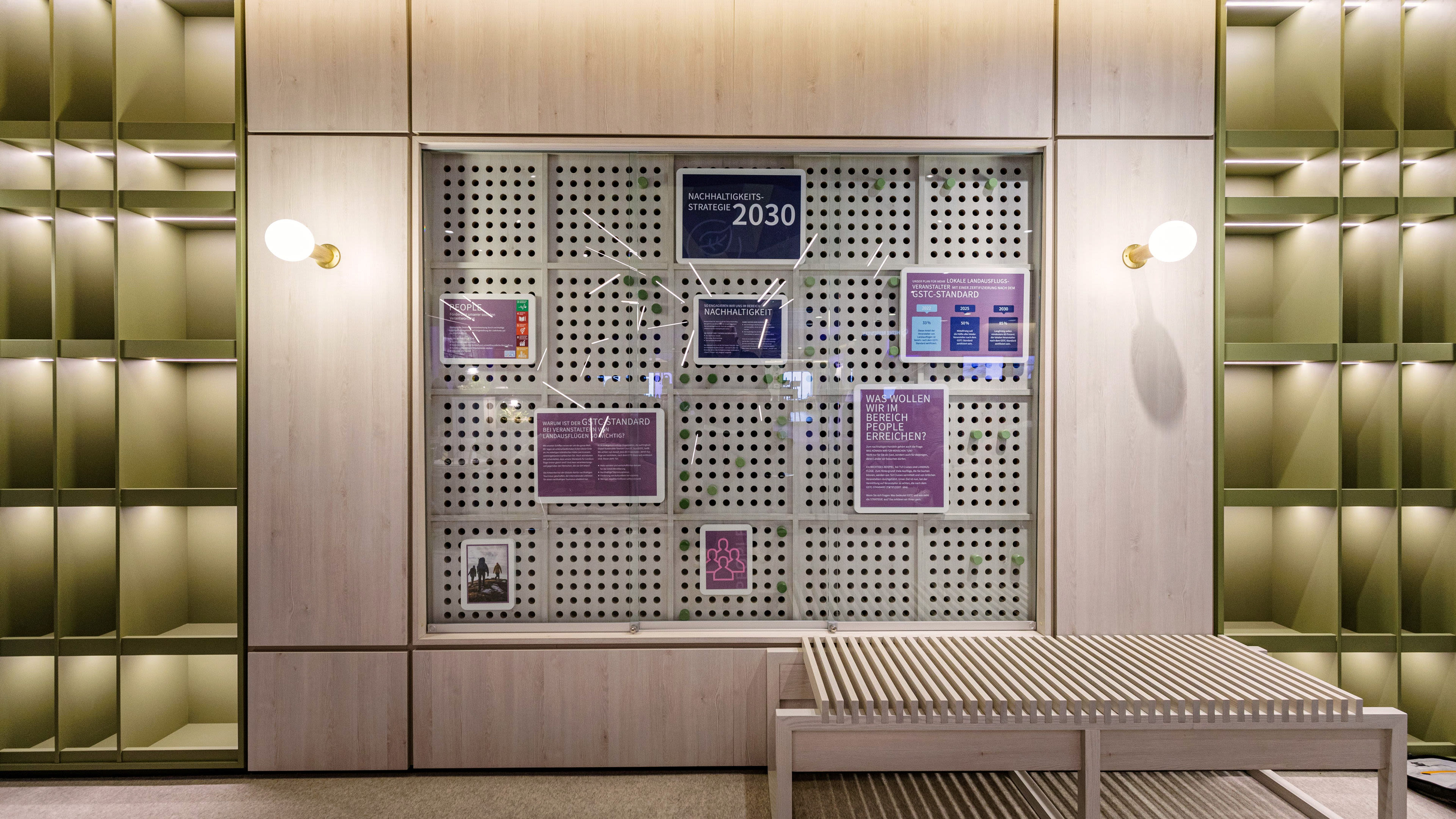 Steckwand zur Nachhaltigkeit in der Grööne Bar - MS3 Holzwand mit Infotafeln zur Nachhaltigkeitsstrategie 2030, grüne Regale.