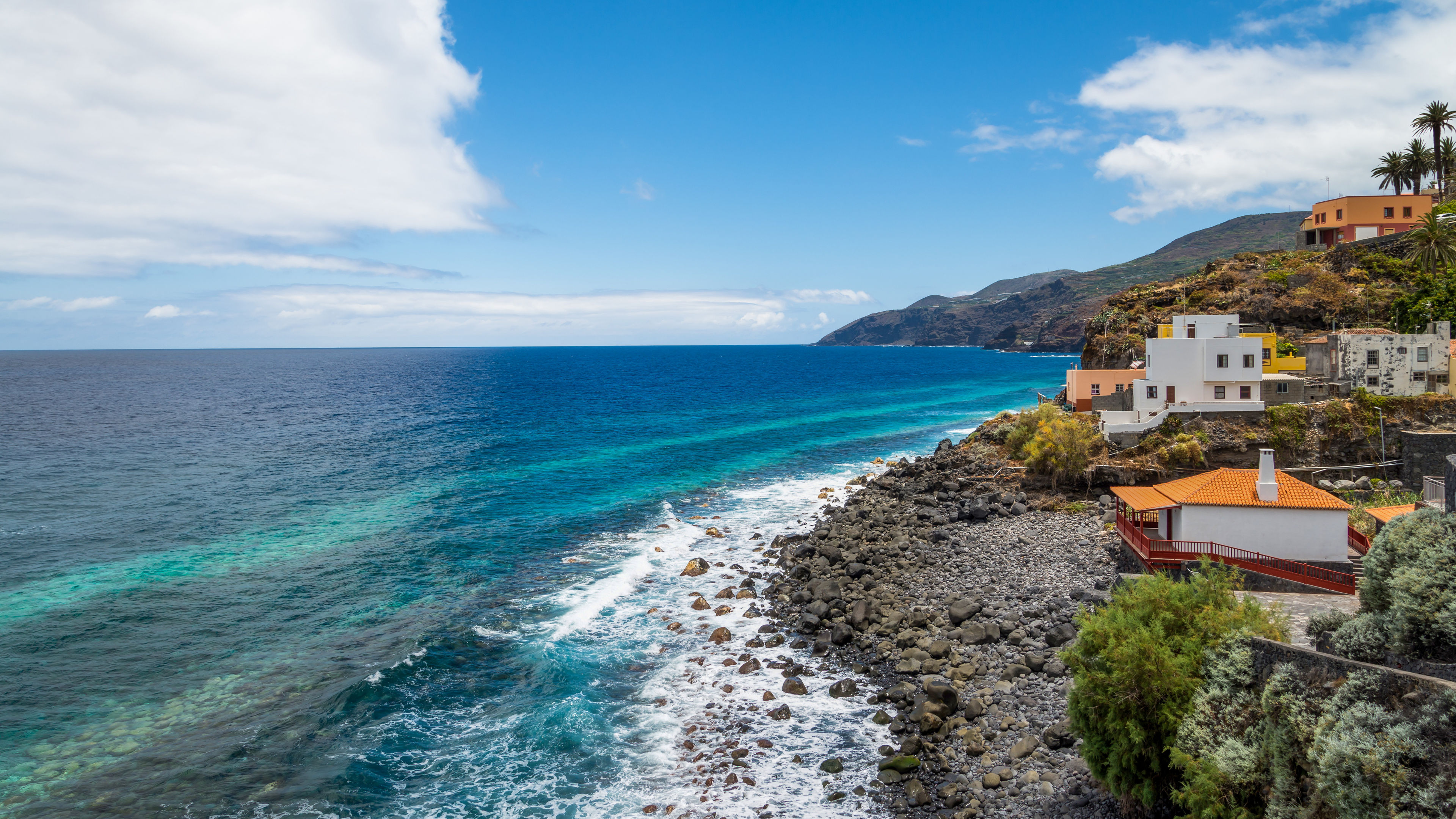 Küste von La Palma, blaues Meer, weiße Häuser, Felsen, Himmel.