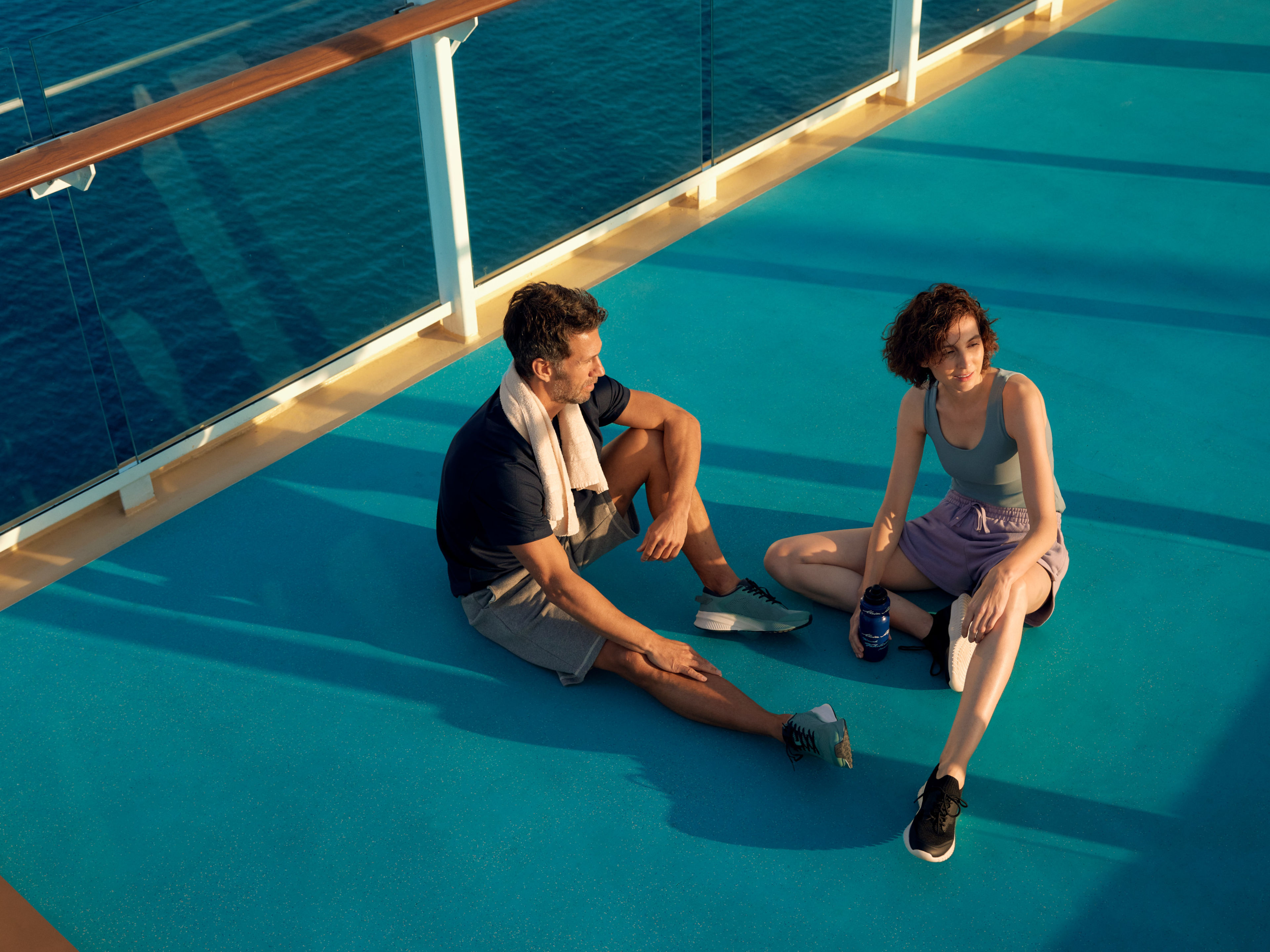 Zwei Personen entspannen auf dem Deck eines Kreuzfahrtschiffs bei Sonnenuntergang. Zwei Personen entspannen auf dem Deck eines Kreuzfahrtschiffs bei Sonnenuntergang.