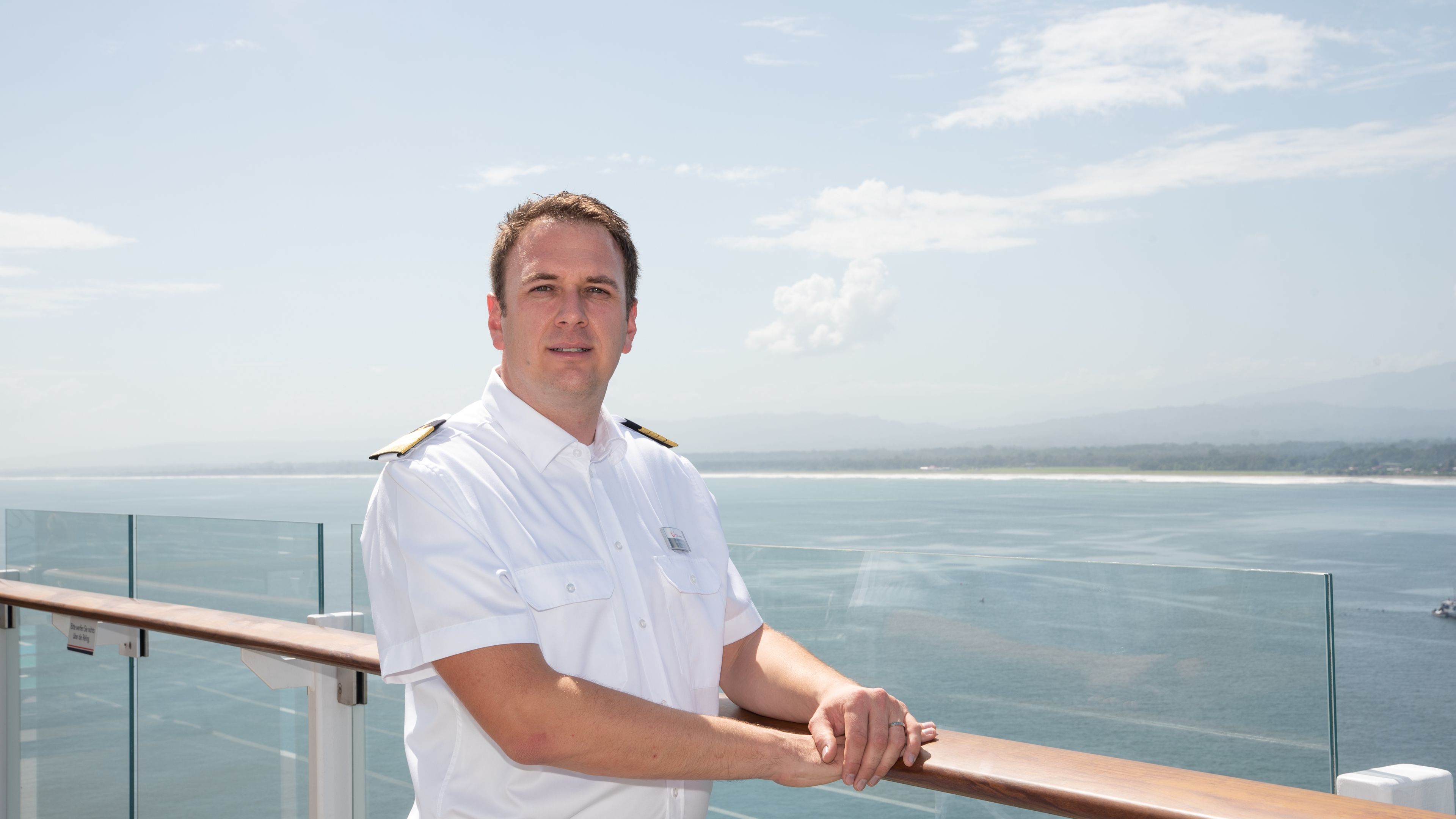 Mann in weißer Uniform auf Kreuzfahrtschiff, Meer im Hintergrund. Mann in weißer Uniform auf Kreuzfahrtschiff, Meer im Hintergrund.