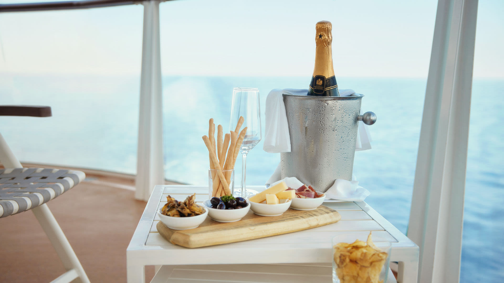 Sektflasche im Eiskübel, Snacks und Meerblick auf Kreuzfahrtschiff.