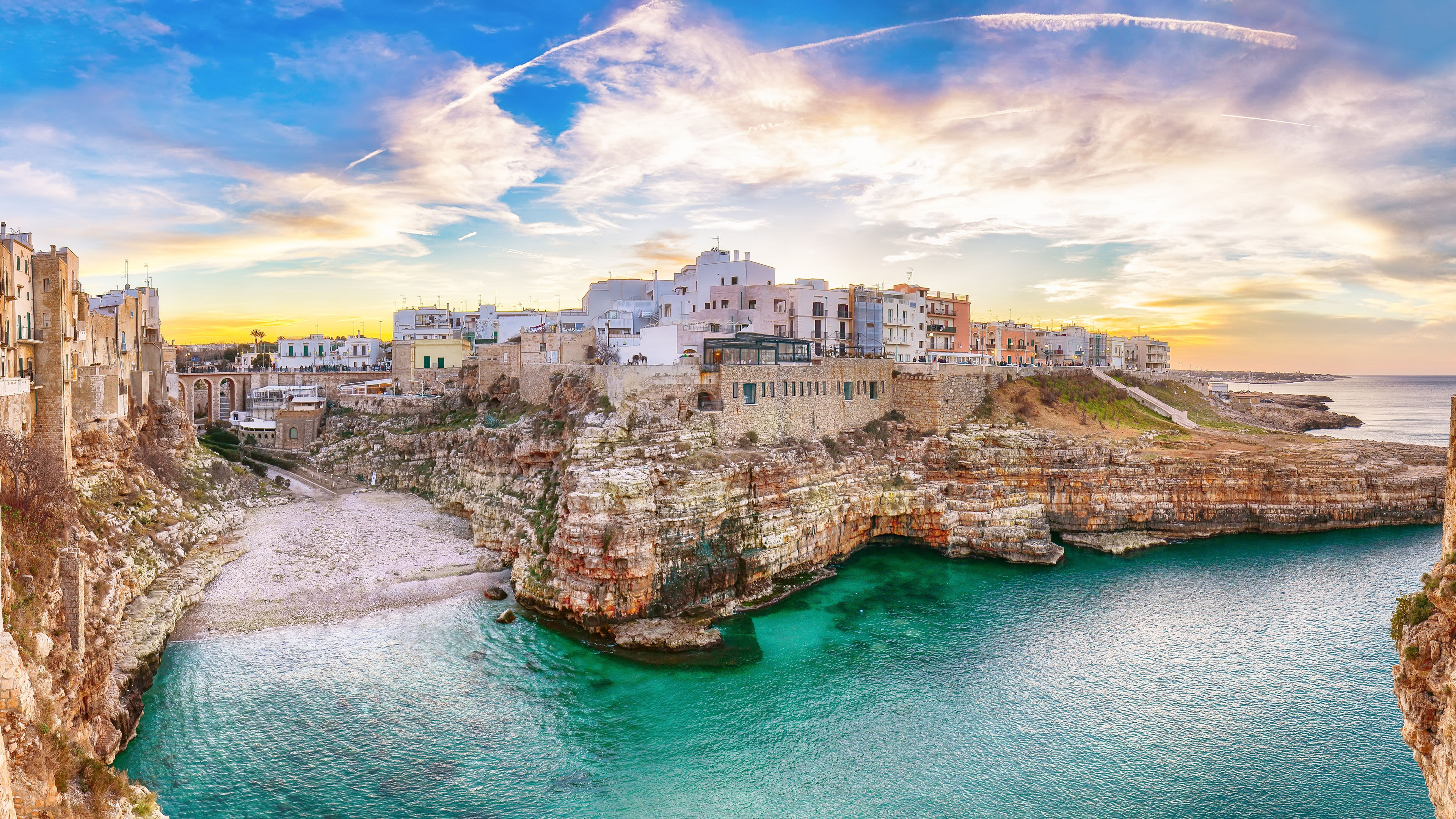 Bari Küstenstadt Polignano a Mare, Italien, bei Sonnenuntergang, türkisfarbenes Meer, historische Gebäude.