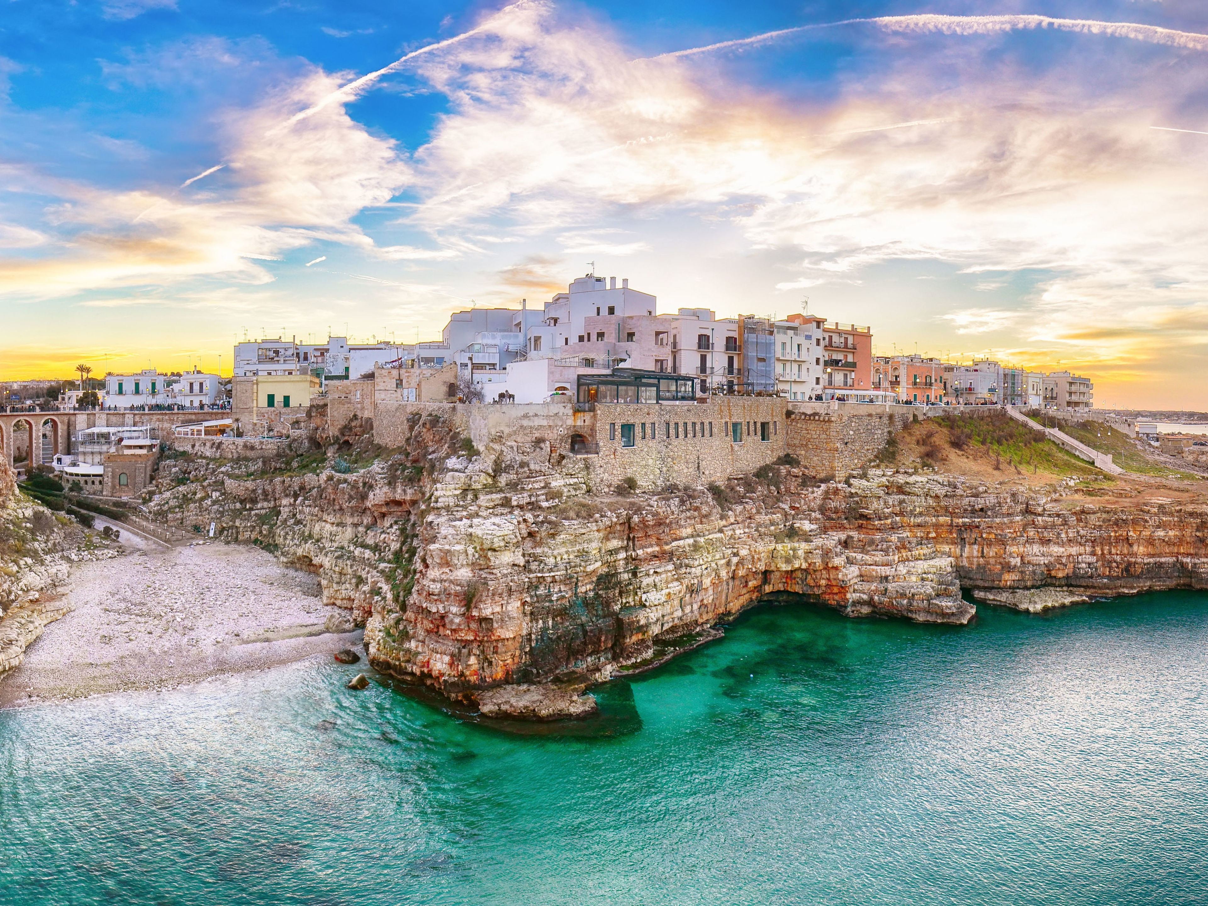 Bari Küstenstadt Polignano a Mare, Italien, bei Sonnenuntergang, türkisfarbenes Meer, historische Gebäude.