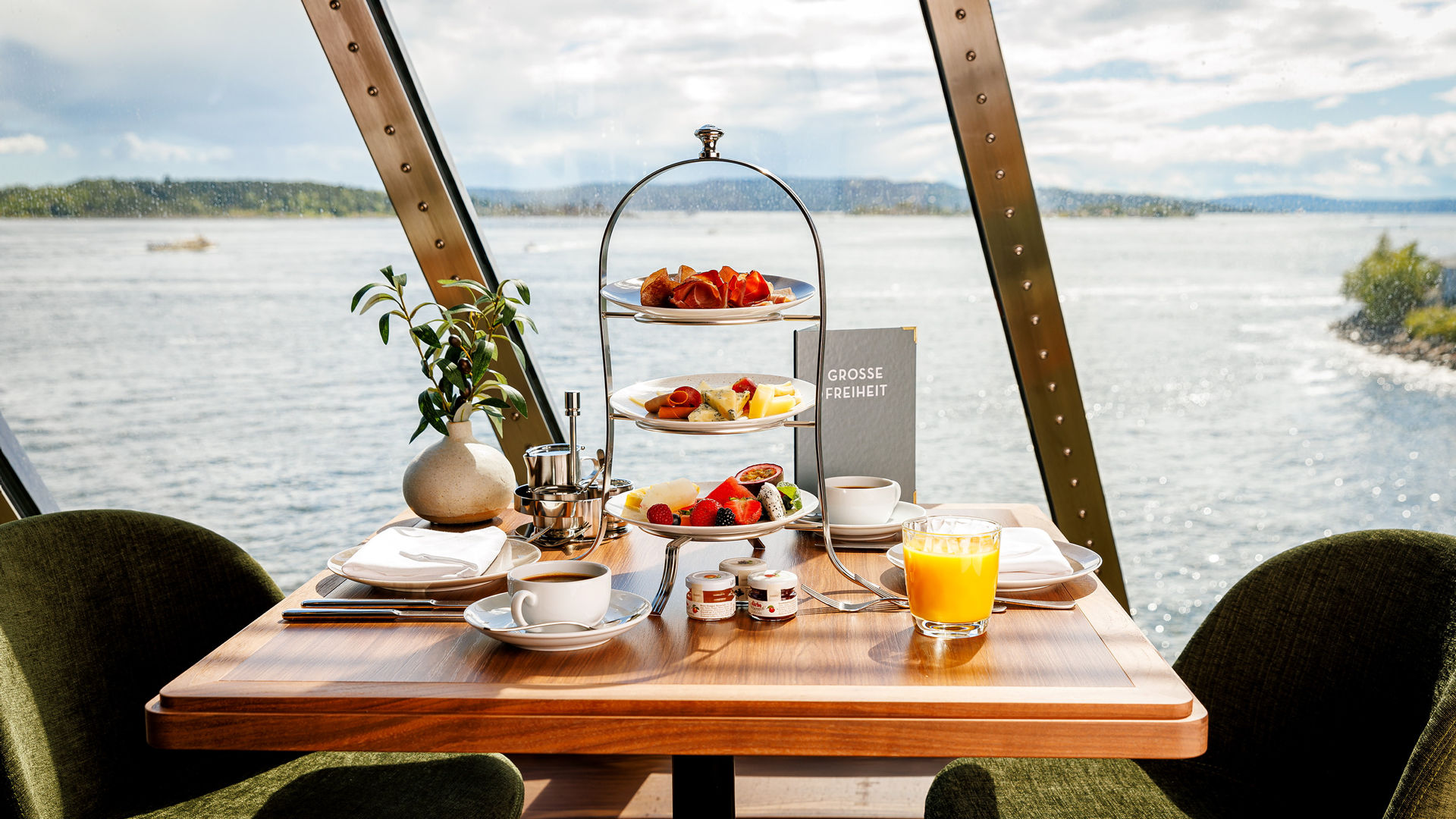 Frühstückstisch mit Obst, Gebäck und Saft, Blick aufs Meer.