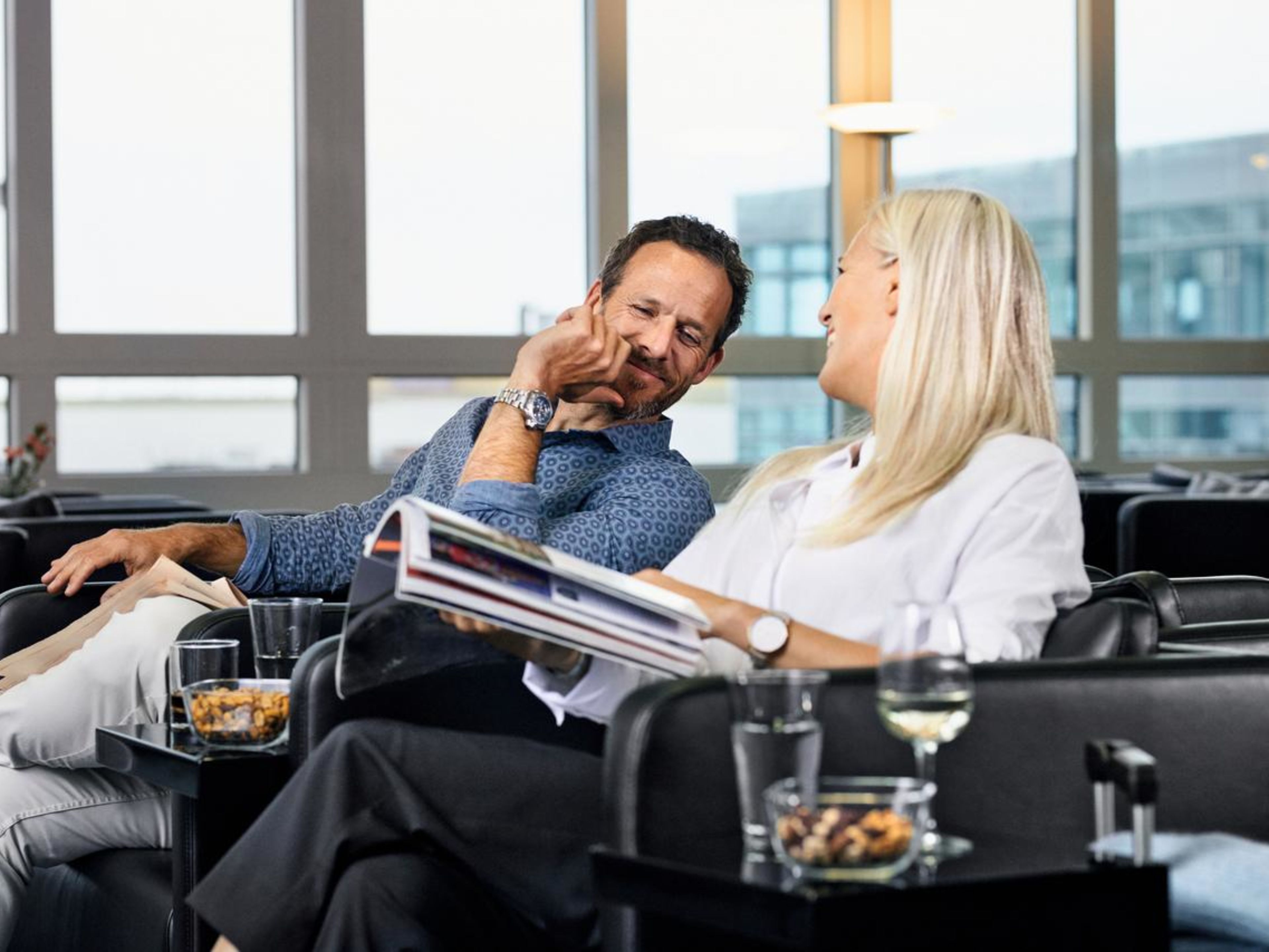 Paar entspannt in Lounge, liest Magazin, trinkt Wein. Paar entspannt in Lounge, liest Magazin, trinkt Wein.