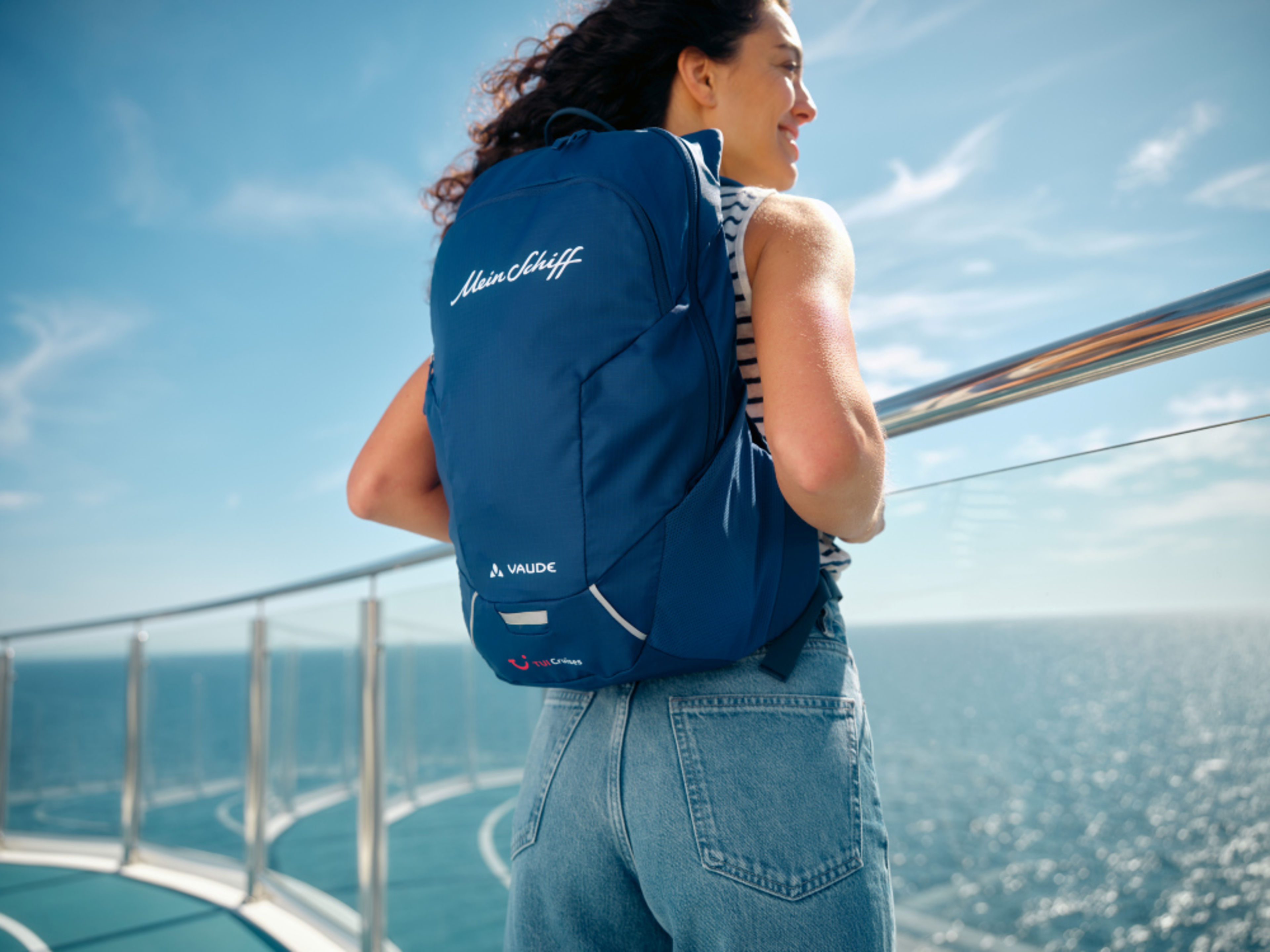 Frau mit blauem Rucksack auf Kreuzfahrtschiff, Meer im Hintergrund. Frau mit blauem Rucksack auf Kreuzfahrtschiff, Meer im Hintergrund.
