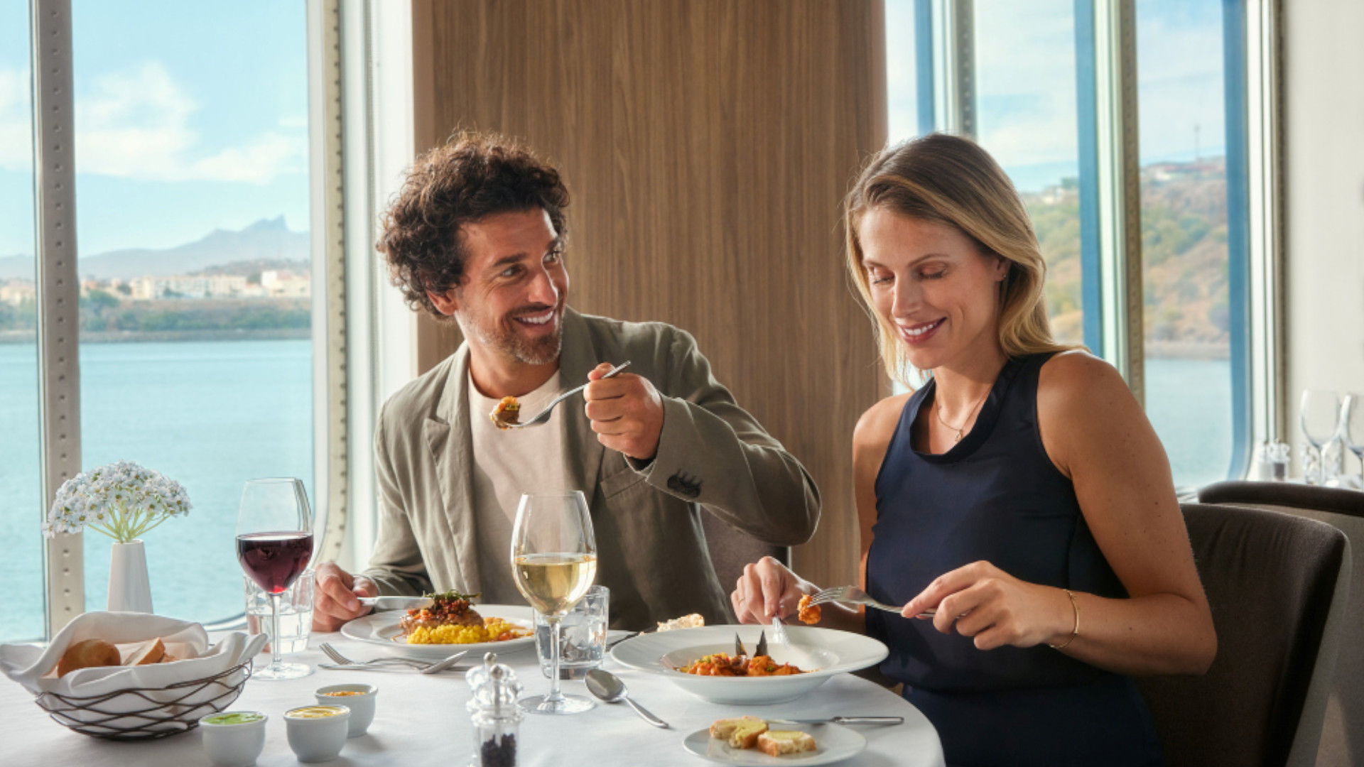 Paar genießt Mittagessen mit Wein am Fenster, Meerblick.