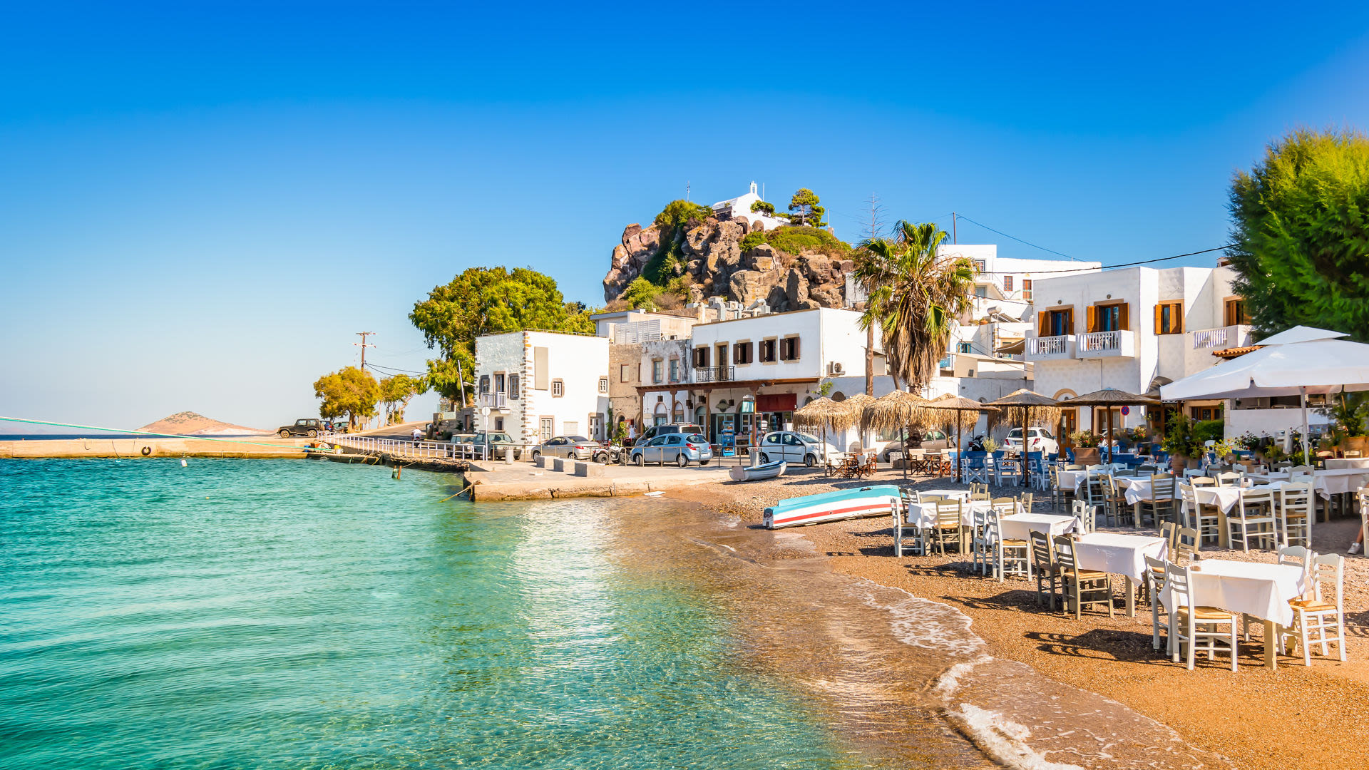 Strandpromenade mit weißen Gebäuden und Tischen, blaues Meer, blauer Himmel. Strandpromenade mit weißen Gebäuden und Tischen, blaues Meer, blauer Himmel.