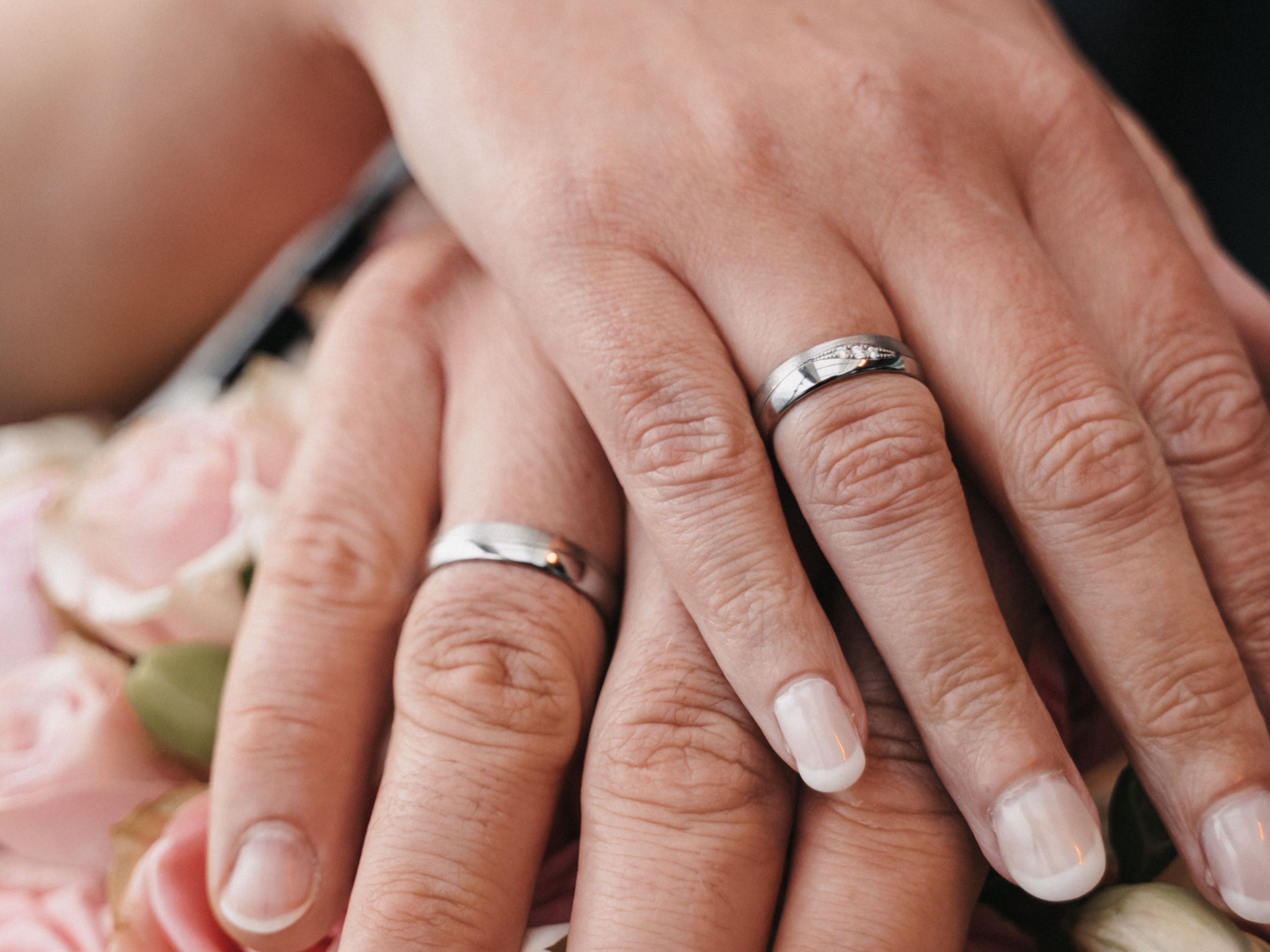Hände mit Eheringen auf rosa Rosenstrauß. Hände mit Eheringen auf rosa Rosenstrauß.