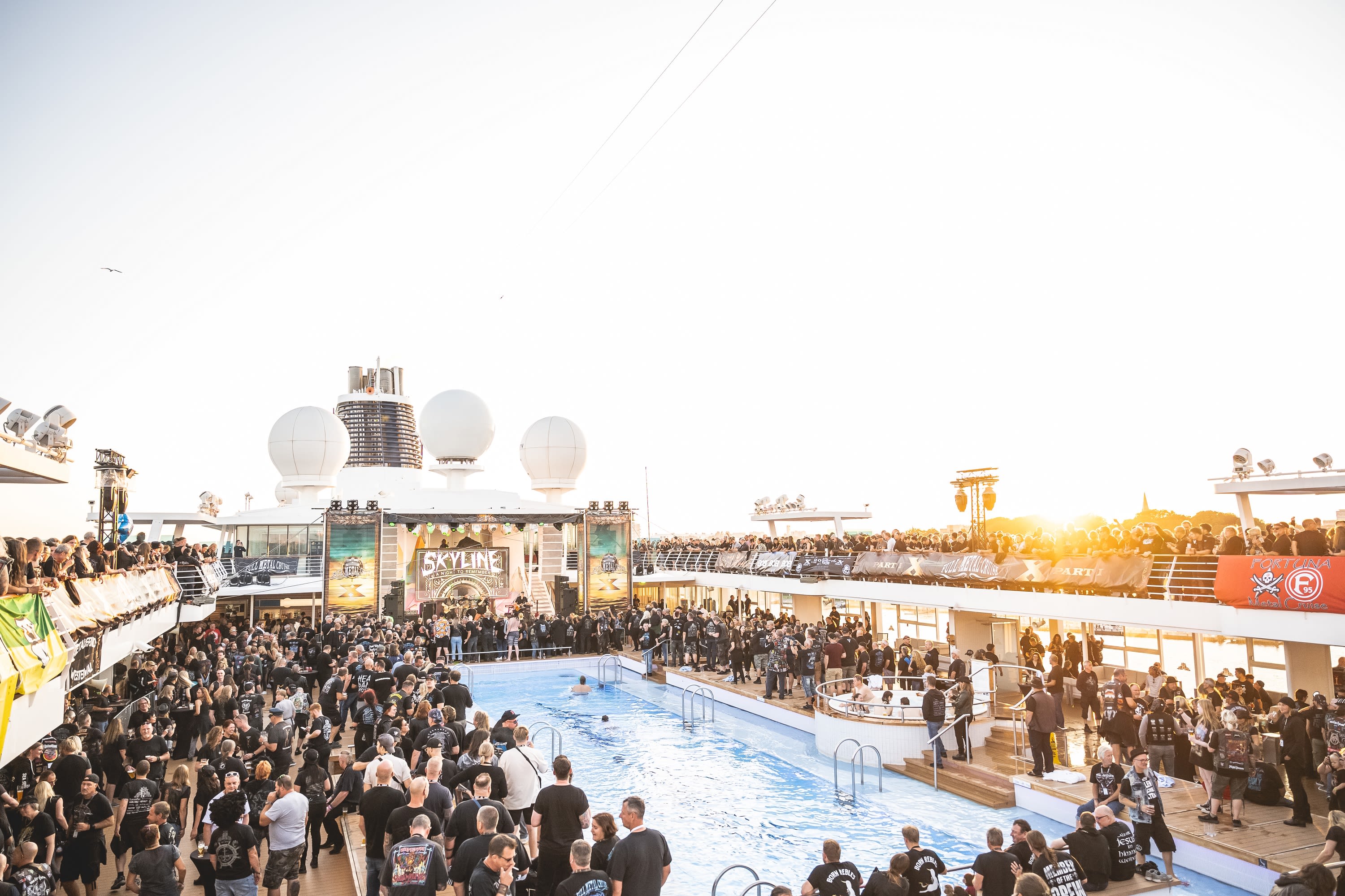 Menschenmenge bei Sonnenuntergang auf Kreuzfahrtschiff der Mein Schiff® Flotte, Pooldeck, Konzertbühne.