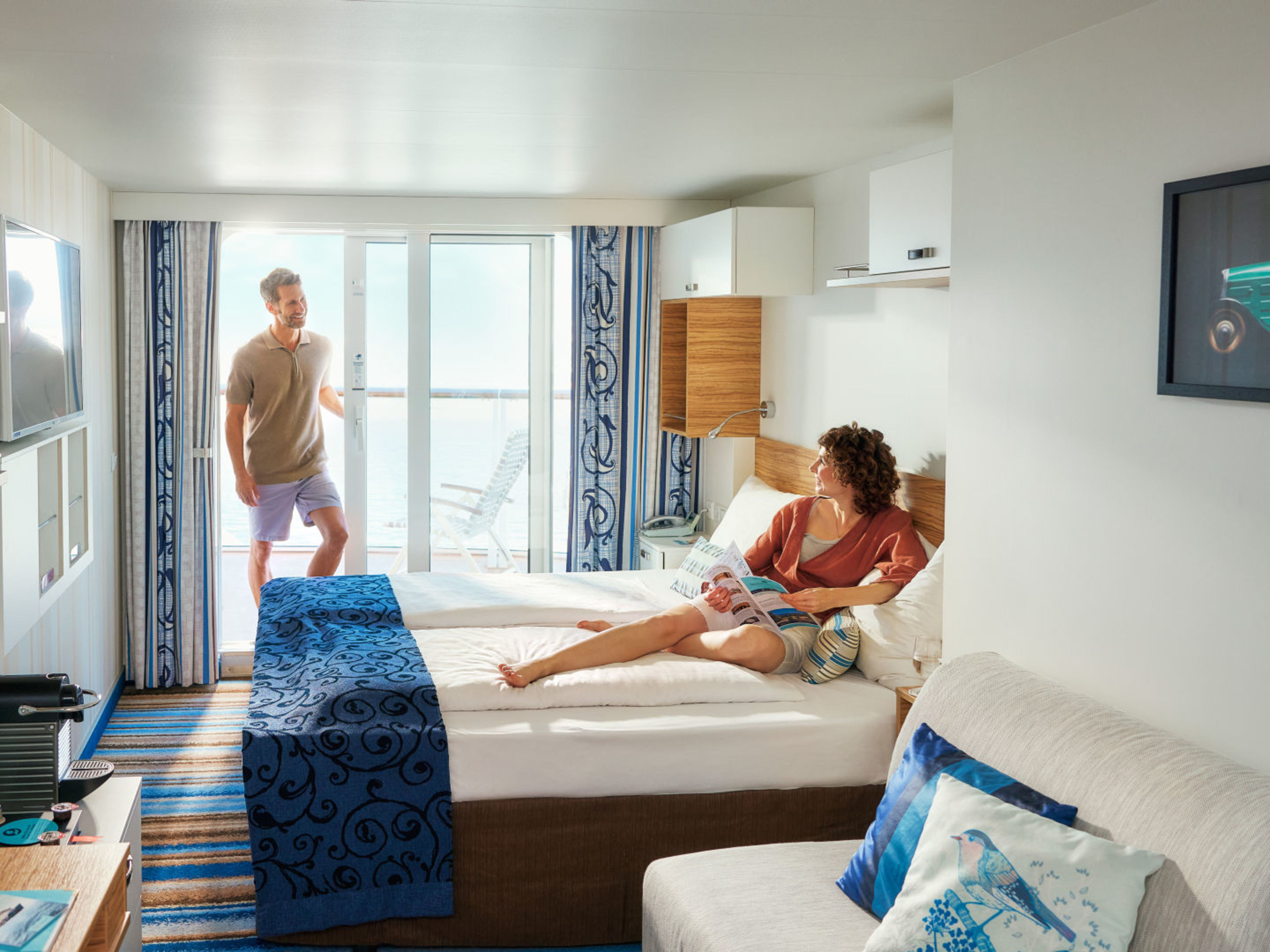 Paar in Kabine Paar entspannt in moderner Kreuzfahrtkabine mit Balkon und Meerblick.