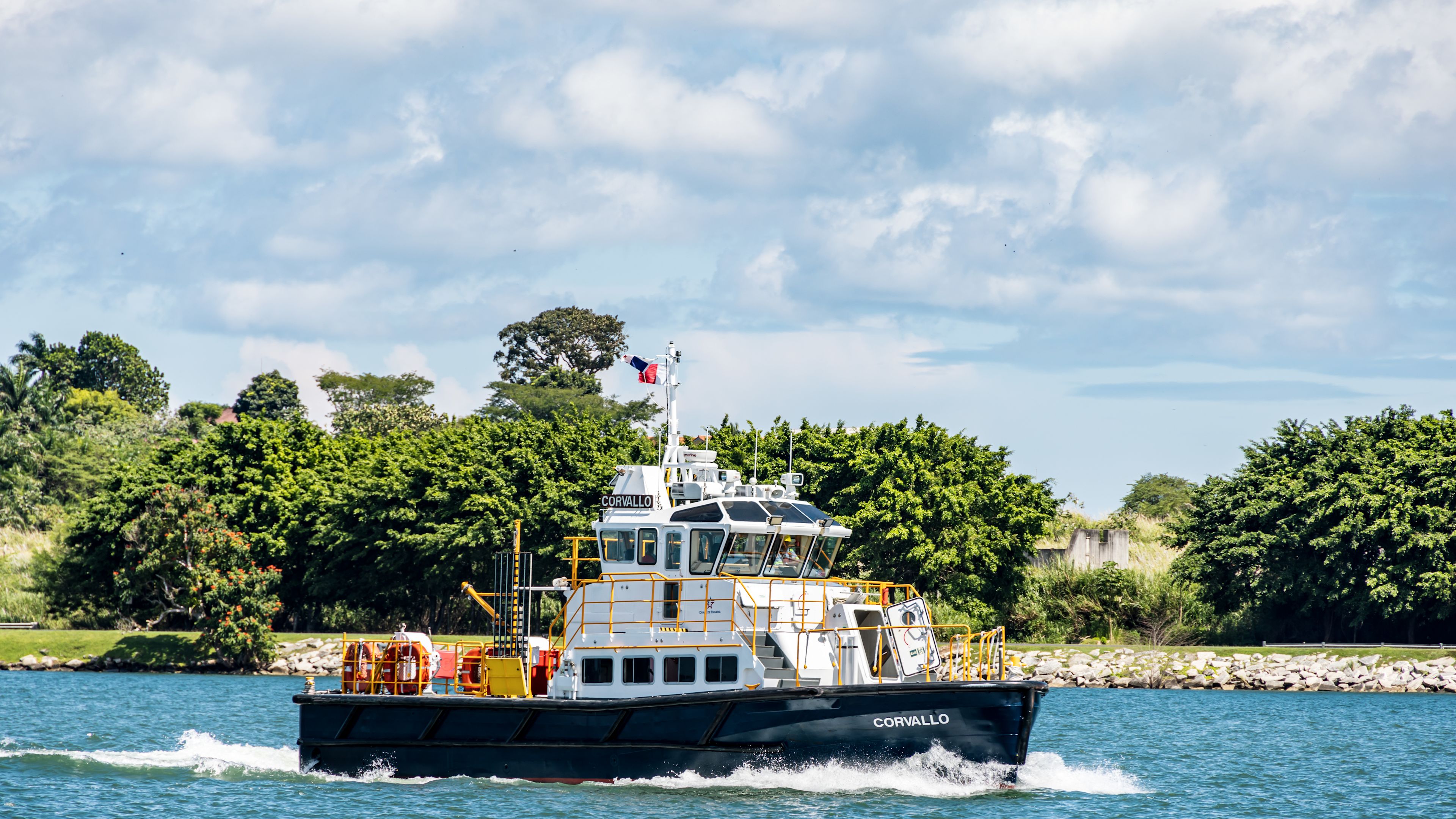 Boot auf blauem Wasser vor grüner Küstenlandschaft. Boot auf blauem Wasser vor grüner Küstenlandschaft.