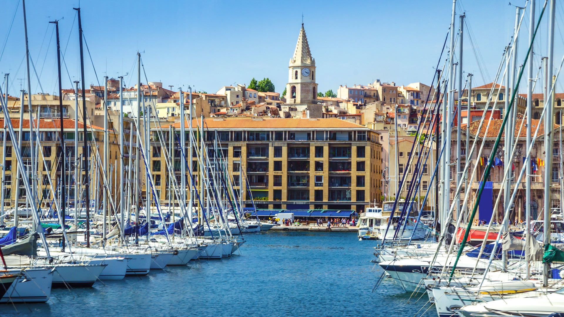 Segelboote im Hafen von Marseille, sonniger Tag, historische Gebäude.