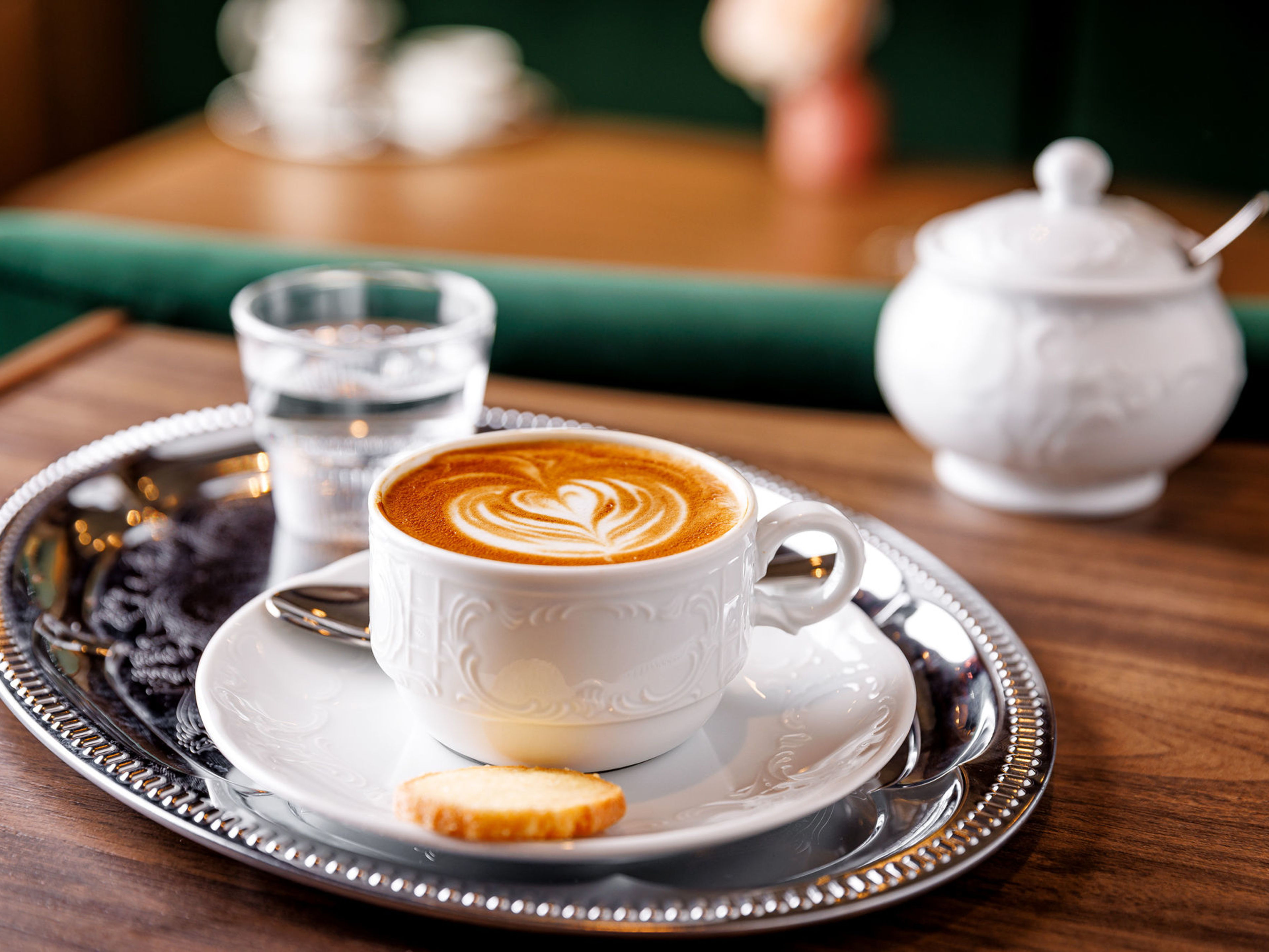 Winer Melange Mein Schiff 7 Kaffee mit Latte Art auf Tablett, Keks, Glas Wasser.