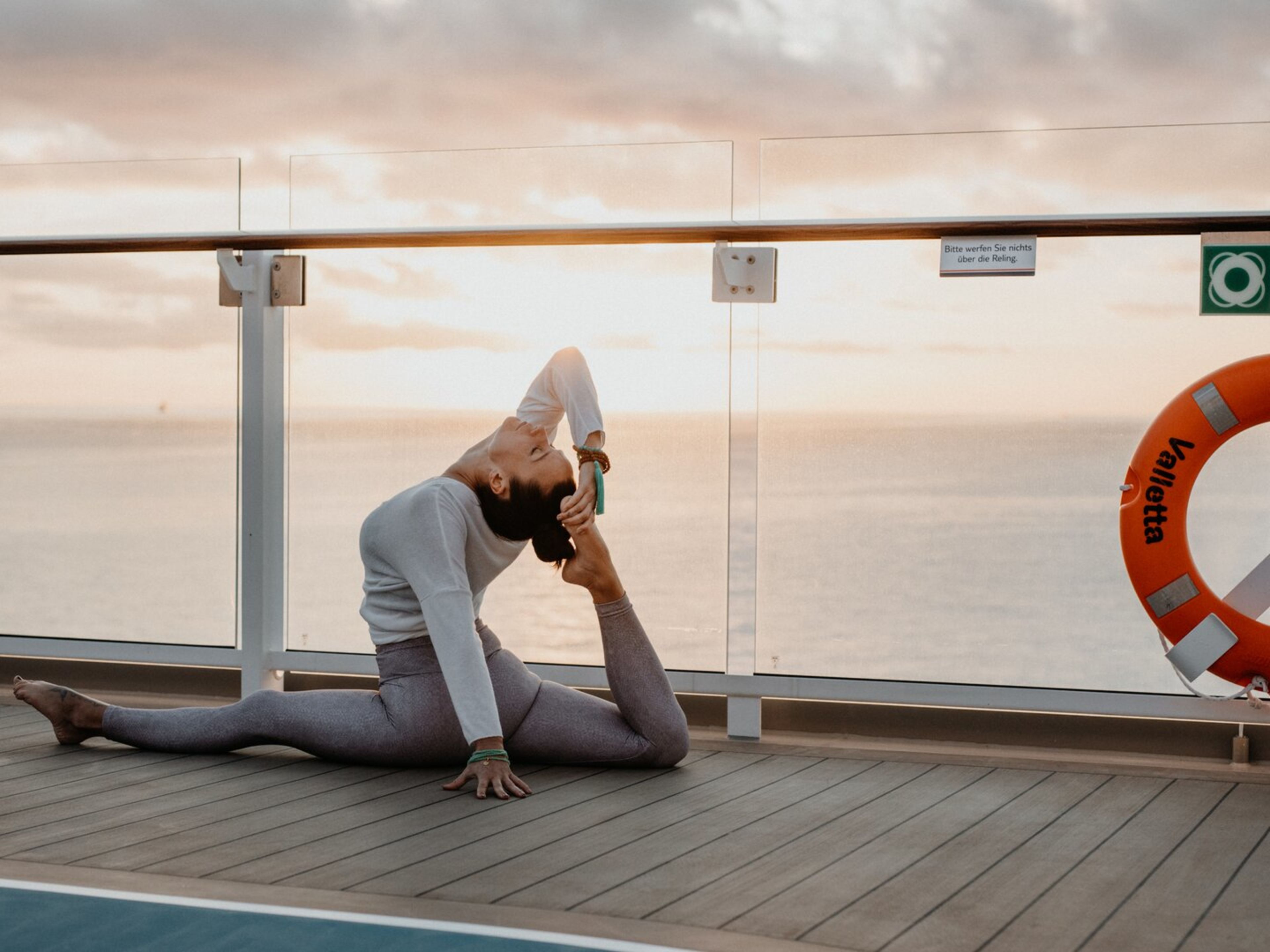 Zeit fuer Yoga und Selbstliebe - Berenice Seiss Frau macht Yoga auf Kreuzfahrtschiff der Mein Schiff® Flotte bei Sonnenuntergang.